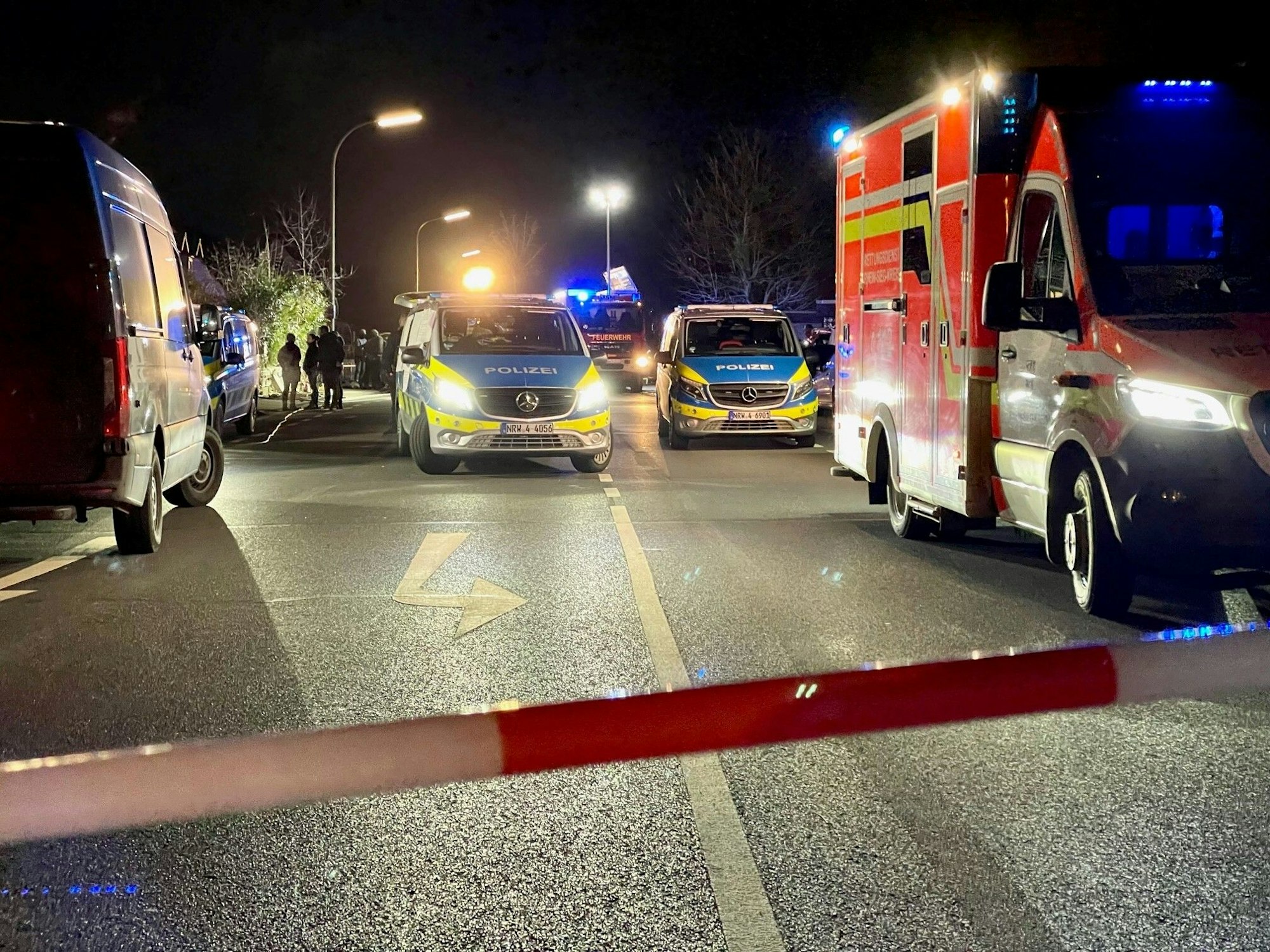Ein Rettungswagen und ein Polizeiauto stehen nachts auf einer Straße.