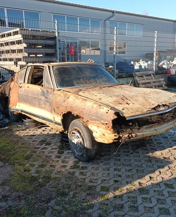 Der verrostete Audi 100 steht auf dem Hof eines Autohauses in Bergheim.