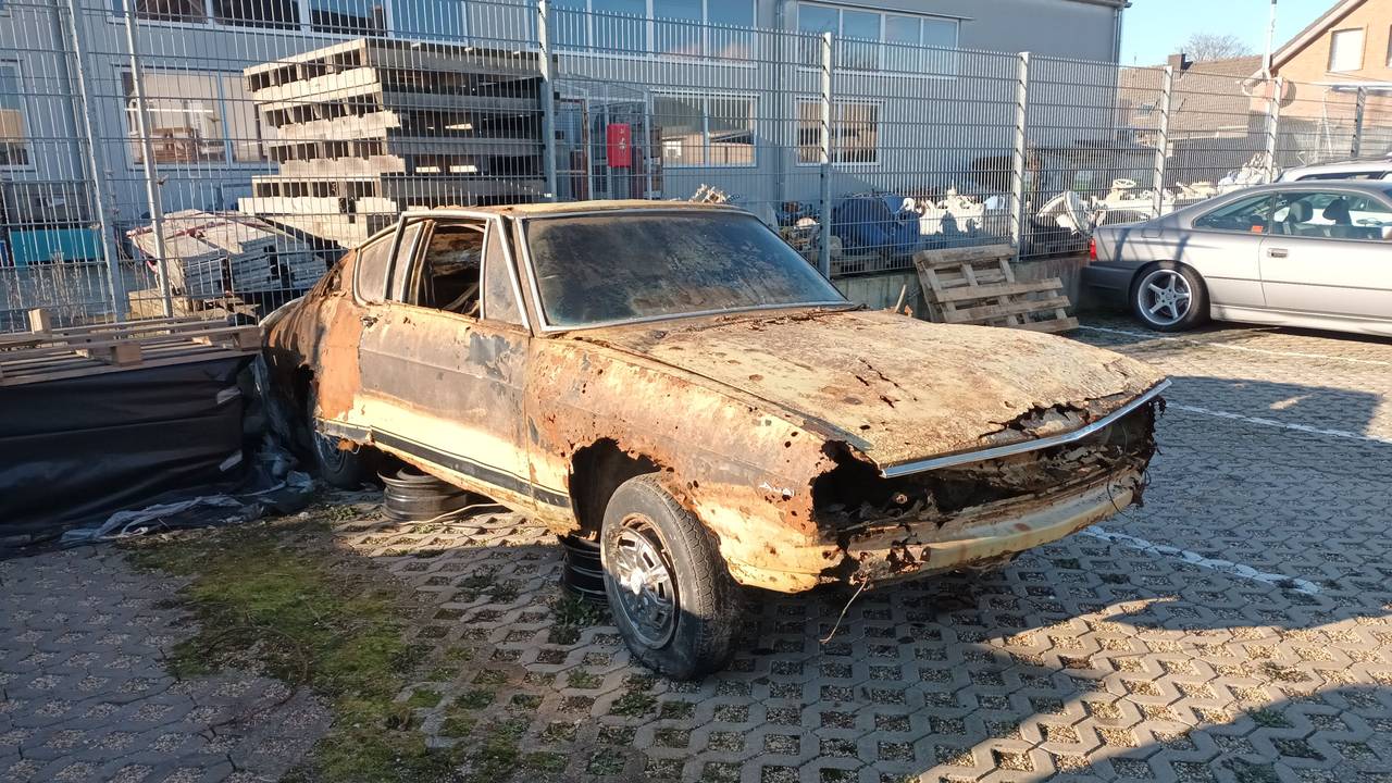 Der verrostete Audi 100 steht auf dem Hof eines Autohauses in Bergheim.