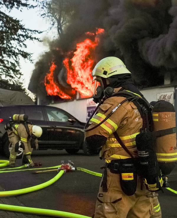 Feuerwehrleute kämpfen gegen einen Brand in einer Lagerhalle in Bergisch Gladbach.