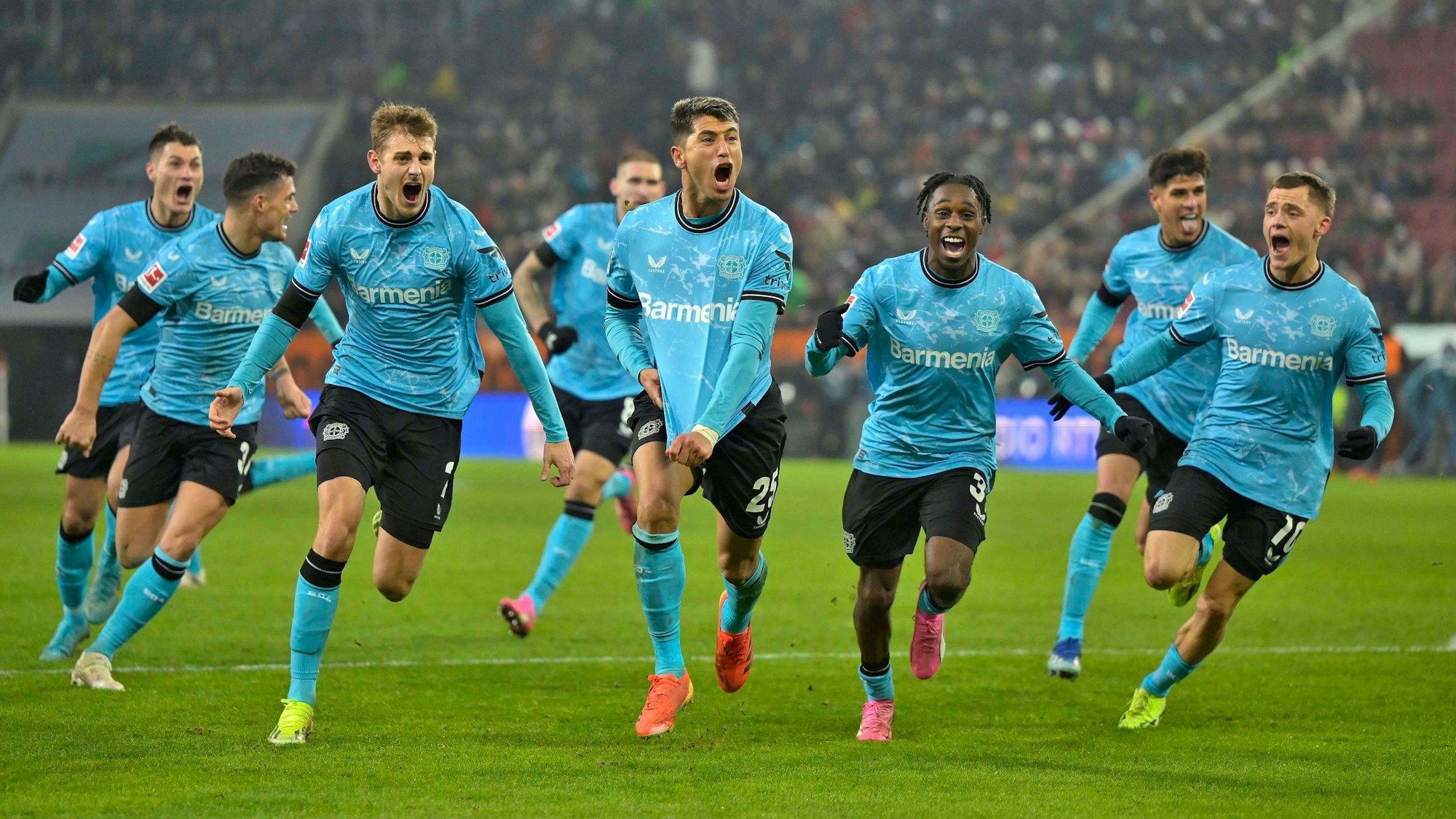 Bayer Leverkusens Exequiel Palacios jubelt mit seinen Kollegen über das späte Siegtor in Augsburg.