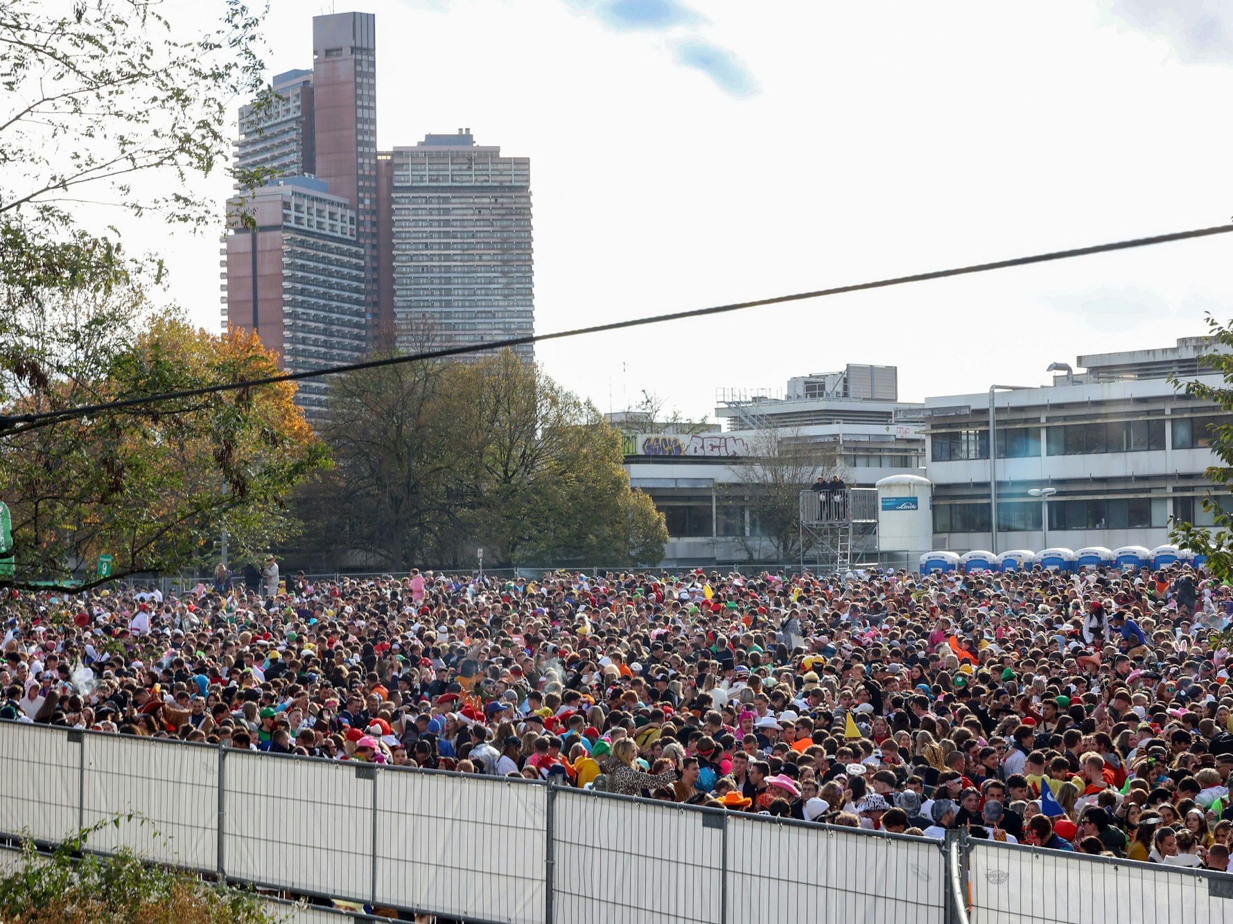 Zahlreiche Menschen stehen in einem abgesperrten Bereich.