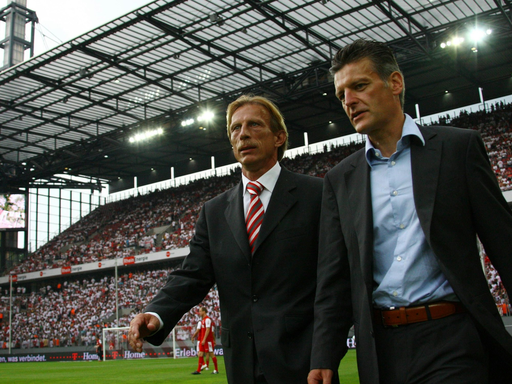 Trainer Christoph Daum (li.) und Pressesprecher Christopher Lymberopoulos betreten gemeinsam den Rasen im Kölner Rhein-Energie-Stadion.