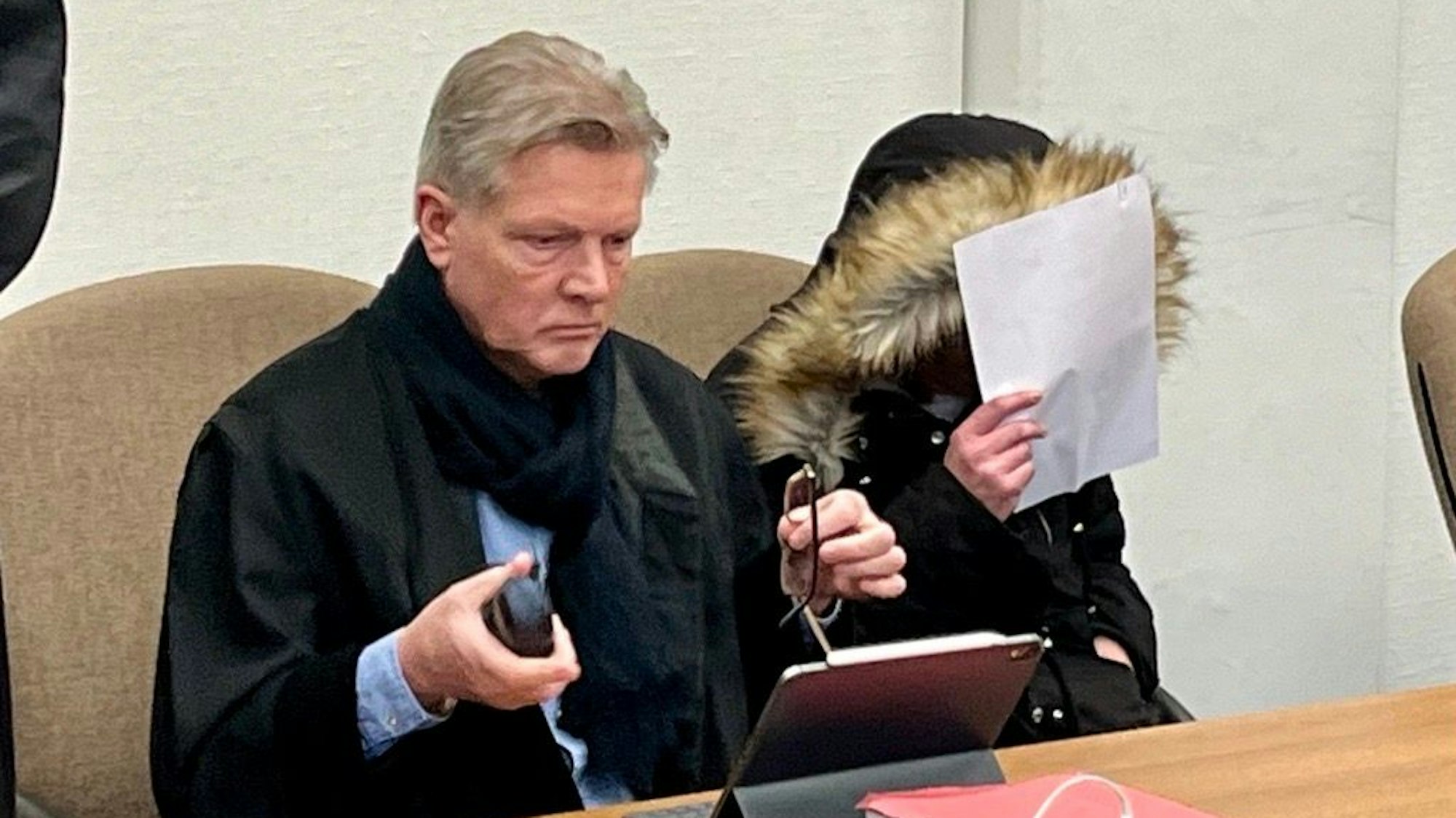 Frau mit schwarzer Jacke sitzt im Gericht neben ihrem Verteidiger.