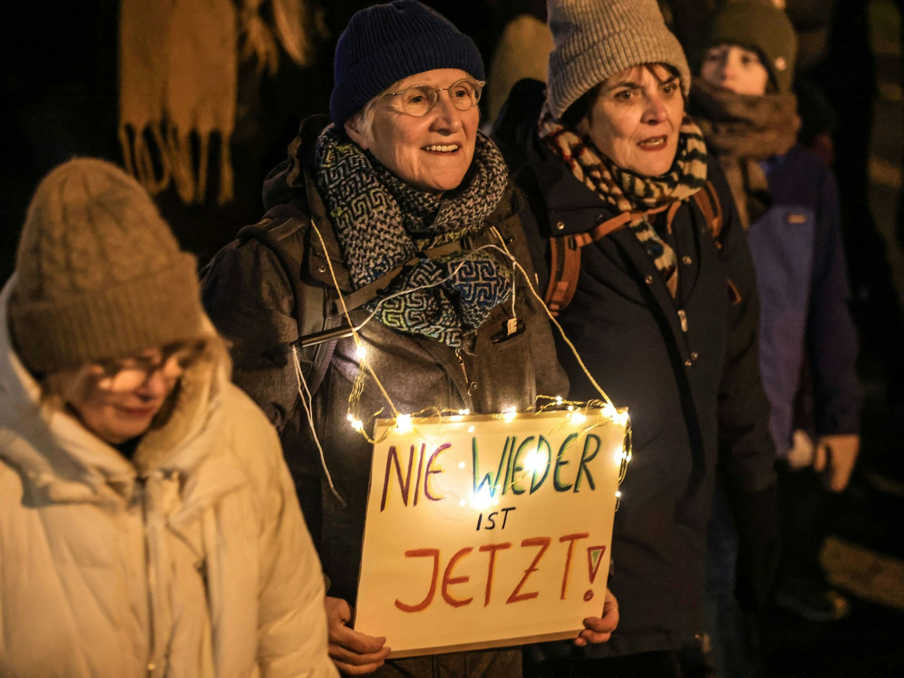 Eine Frau trägt ein Schild mit der Aufschrift „Nie wieder ist jetzt“.