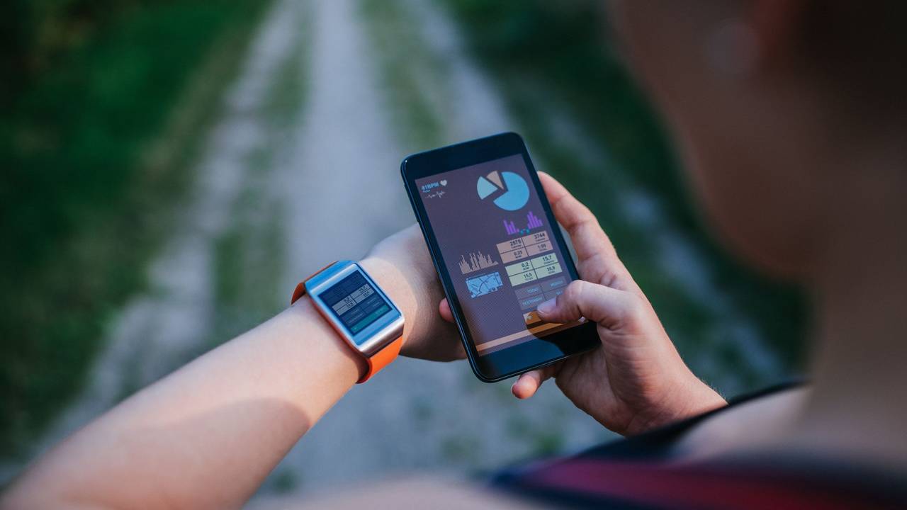 Eine Frau synchronisiert ihre Smartwatch mit ihrem Handy.