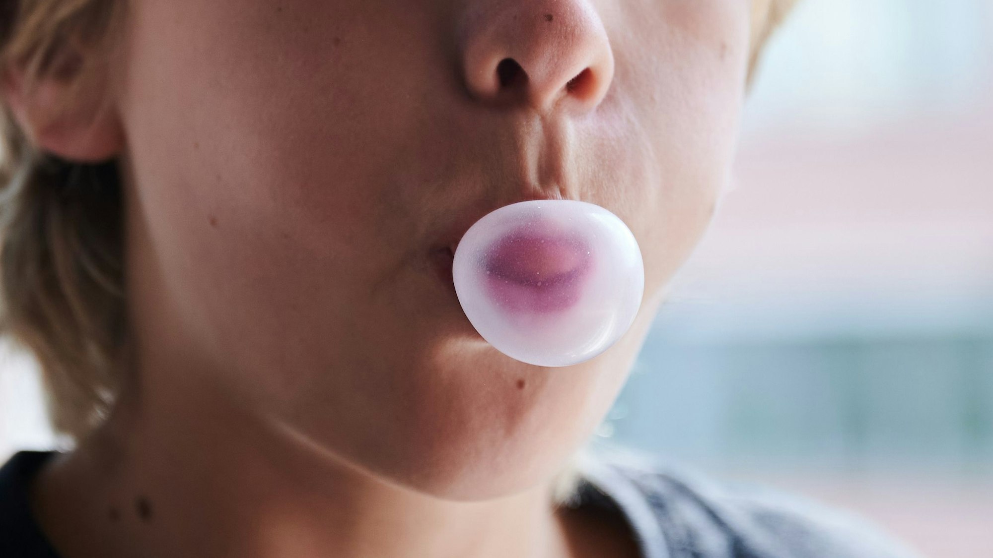Ein Kind formt mit dem Mund eine Kaugummiblase.