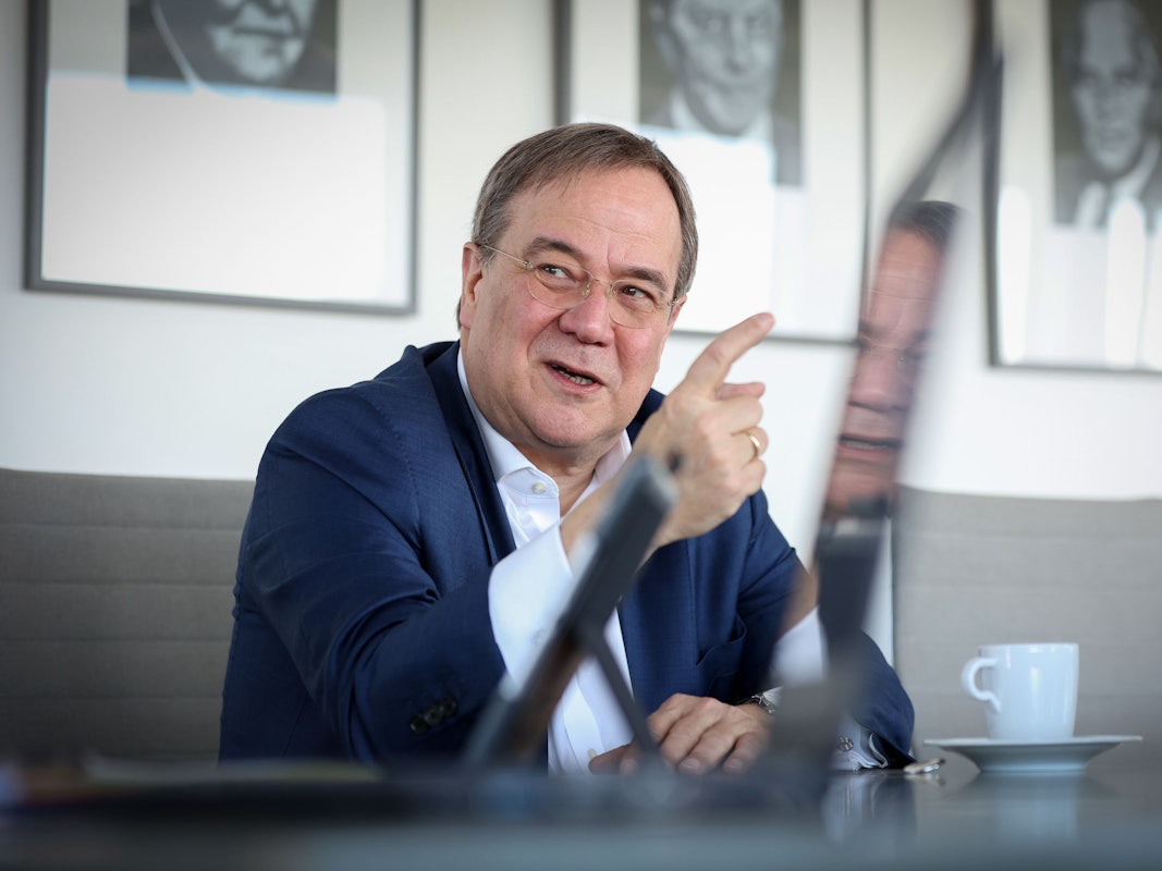 Armin Laschet sitzt im Anzug bei einem Interview und gestikuliert mit seinem Zeigefinger.
