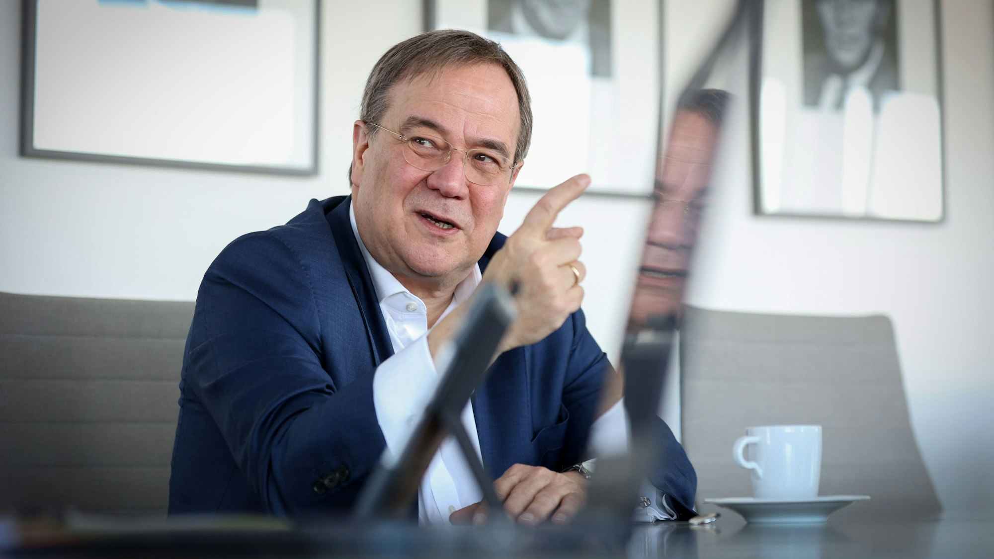 Armin Laschet sitzt im Anzug bei einem Interview und gestikuliert mit seinem Zeigefinger.