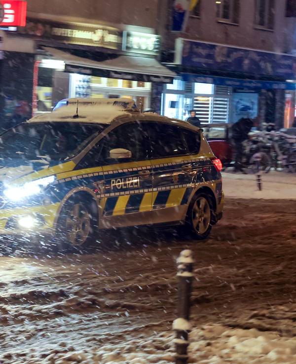 Ein Polizeifahrzeug fährt über die zugeschneite Venloer Straße.