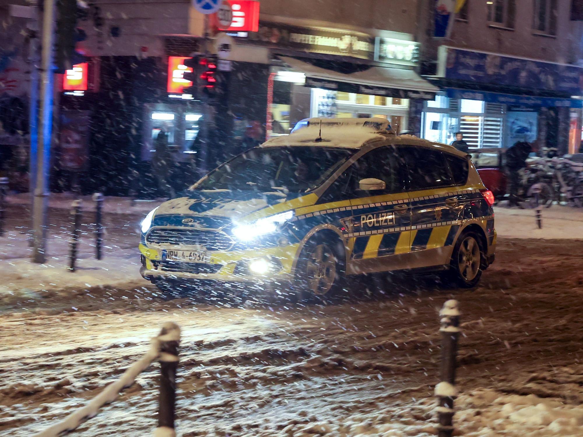 Ein Polizeiwagen fährt abends auf der Venloer Str. bei Schneetreiben.