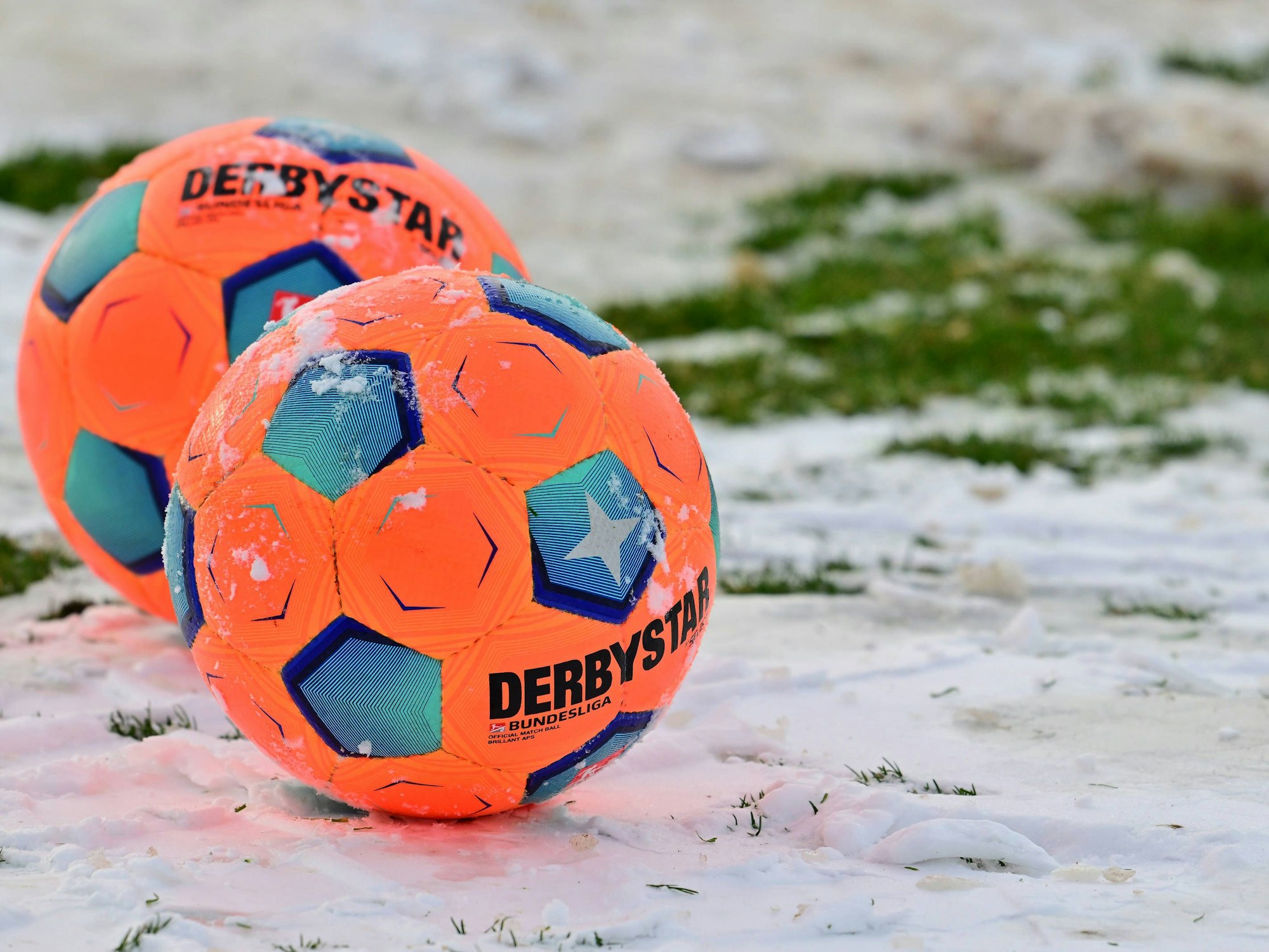 Zwei orange Bälle im Schnee.