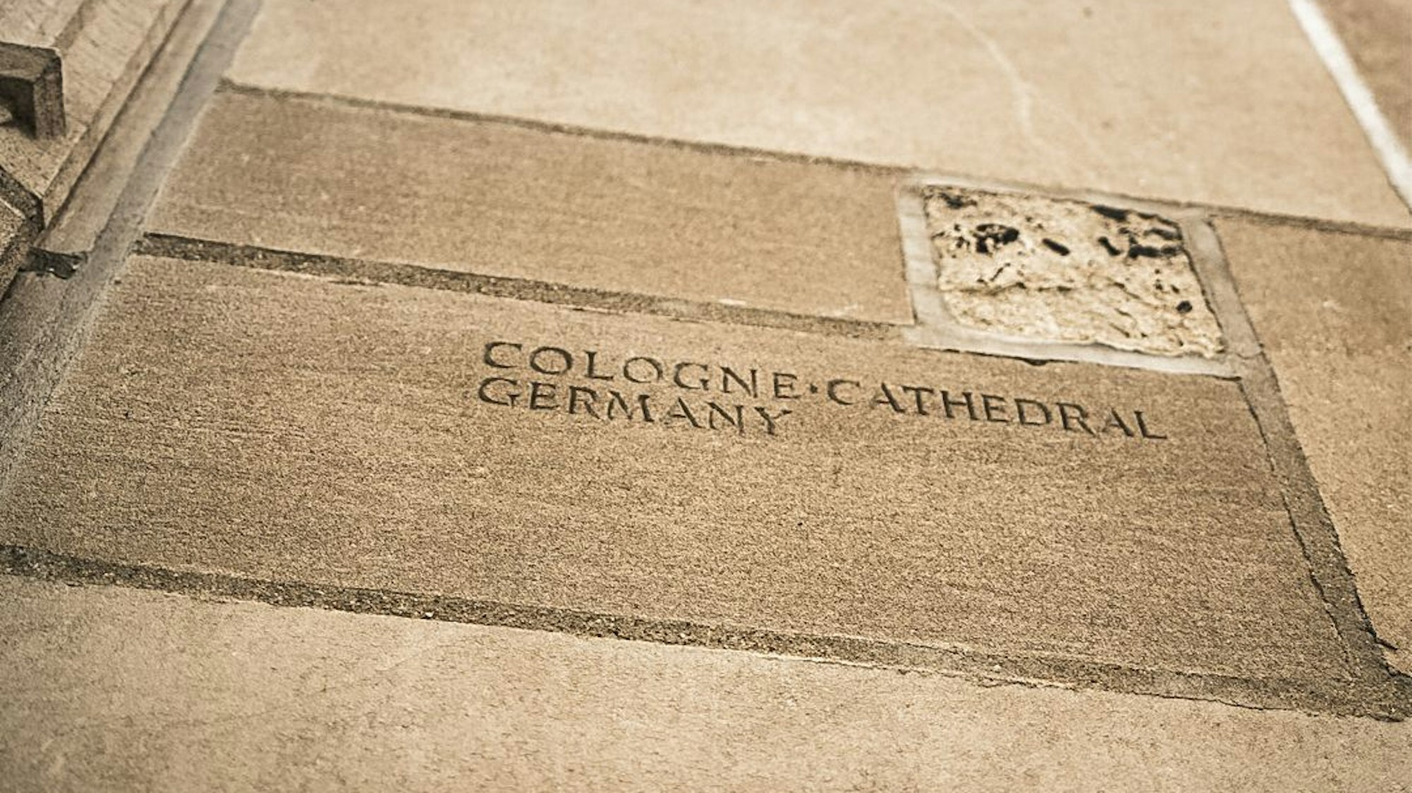 Ein Stein des Kölner Doms mit Inschrift.