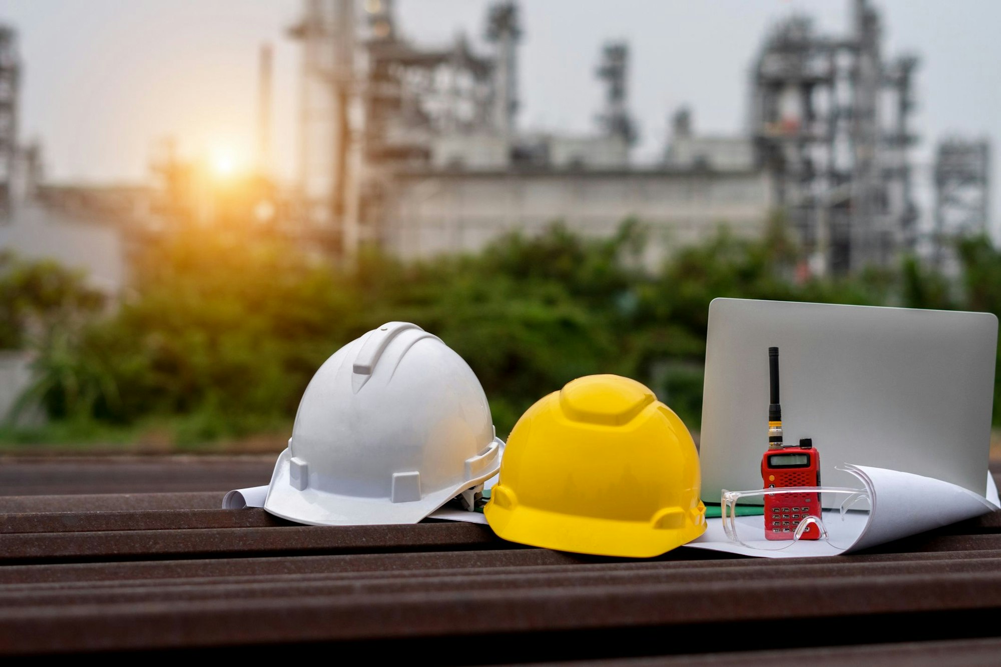 Zwei Helme liegen neben einem Laptop und Plänen auf einem Tisch