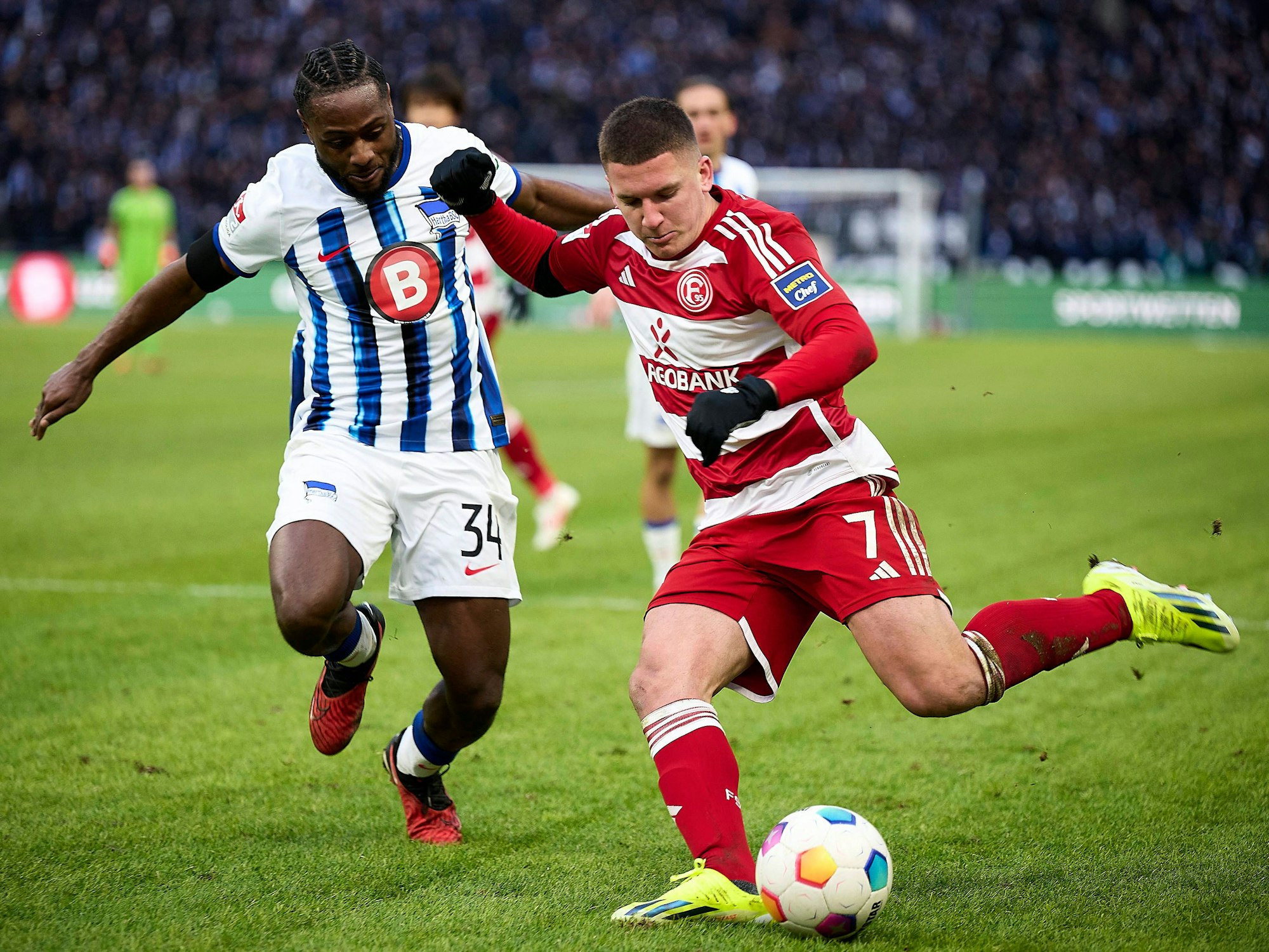 Fortuna Düsseldorfs Christos Tzolis flankt, Herthas Deyovaisio Zeefuik kommt zu spät.