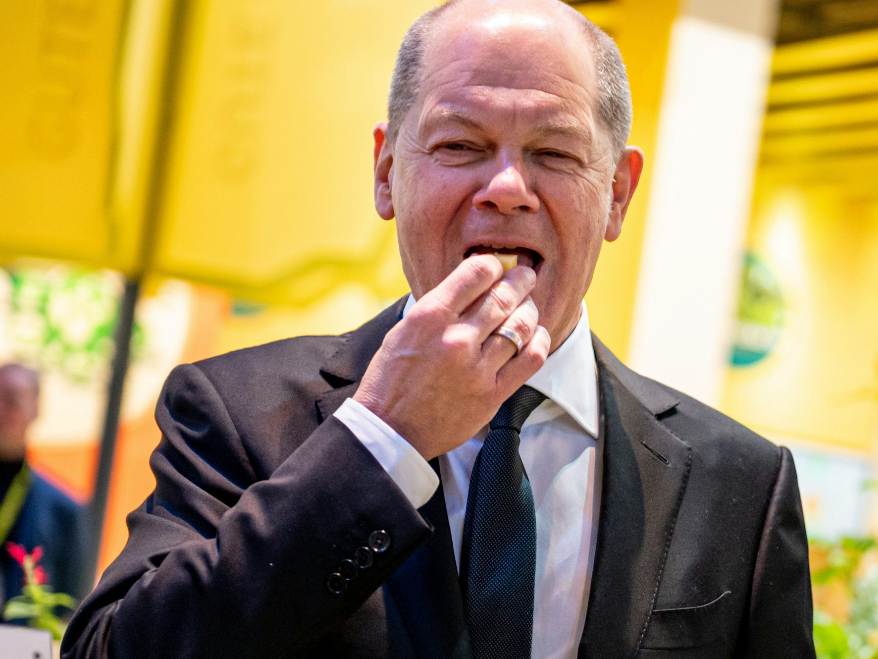 Bundeskanzler Olaf Scholz (SPD) probiert auf der Grünen Woche am Stand für Ökolandbau ein Stück Käse.