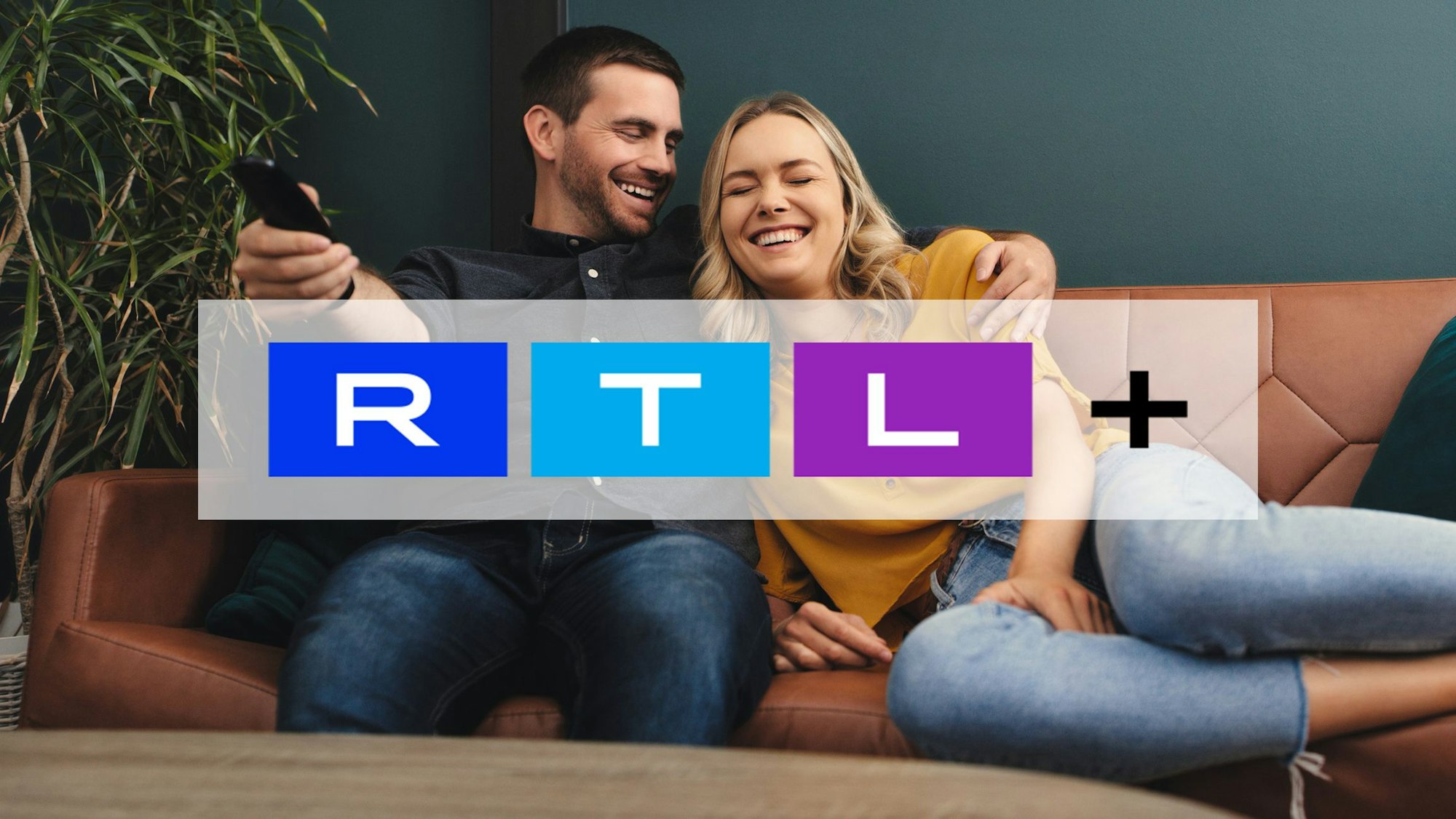 Mann und Frau liegen Arm in Arm auf der Couch und schauen TV