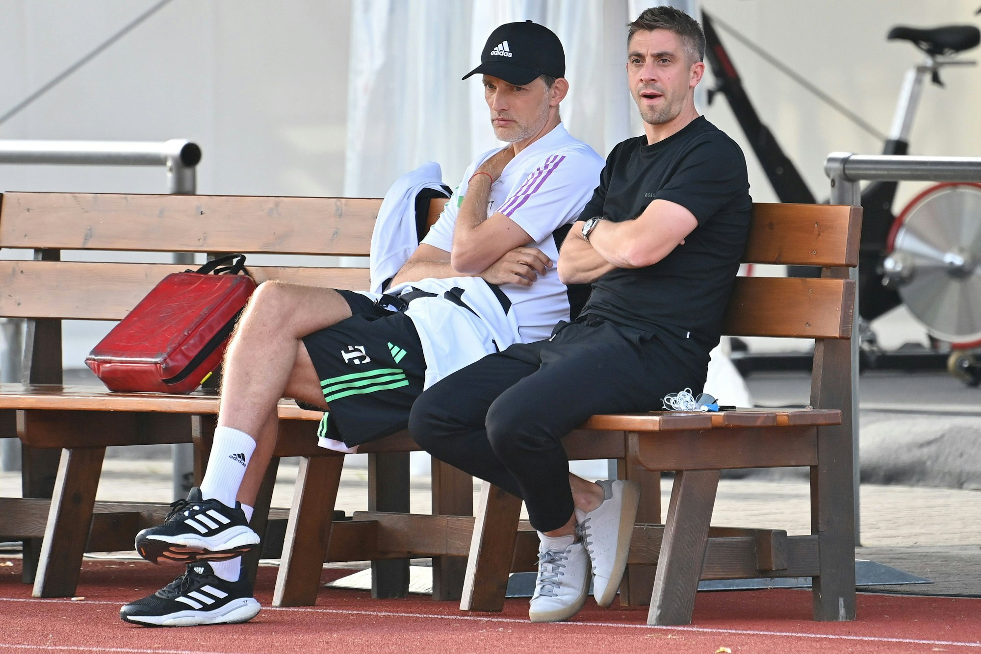 Marco Neppe sitzt neben Thomas Tuchel auf einer Holzbank.