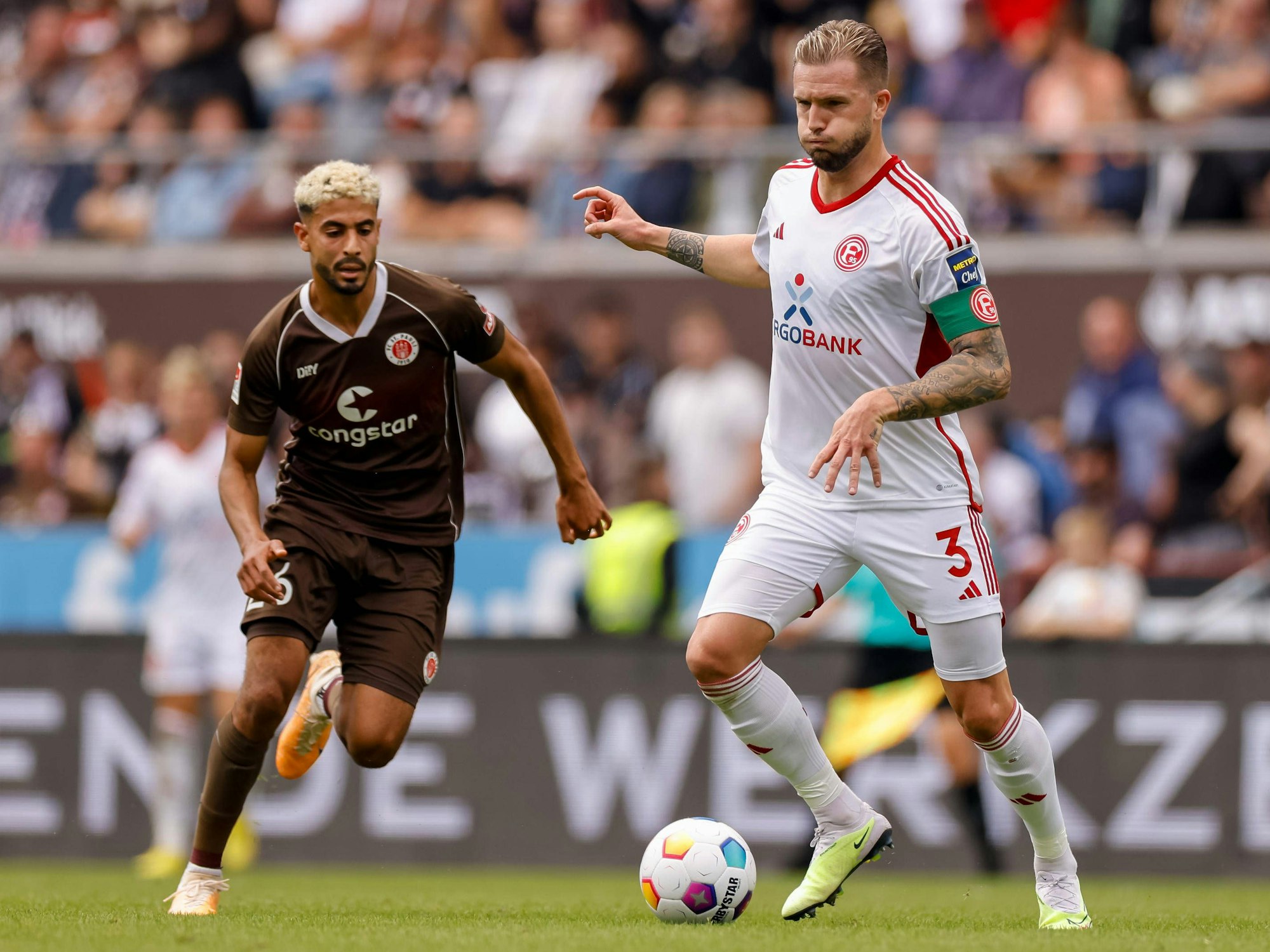 Fortuna Düsseldorfs Kapitän Andre Hoffmann passt den Ball, im Hnitergrund läuft St. Paulis Elias Saad.