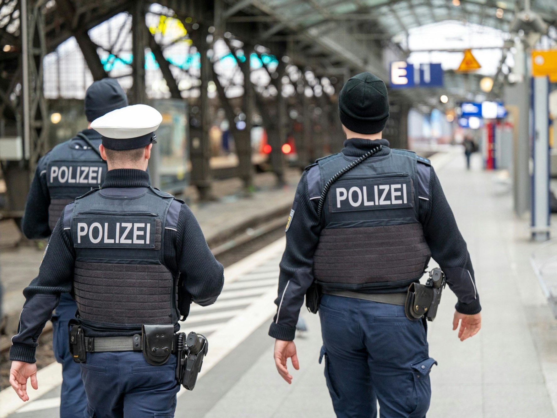 Drei Polizisten laufen im Kölner Hauptbahnhof auf einem Bahnsteig entlang.