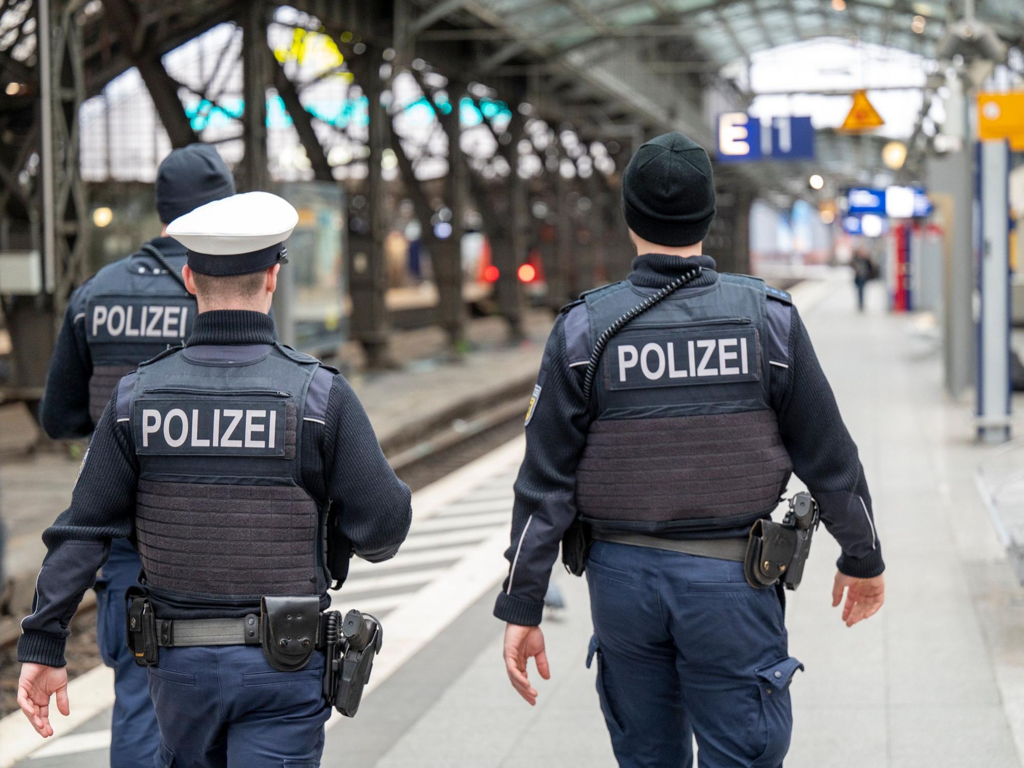 Drei Polizisten laufen im Kölner Hauptbahnhof auf einem Bahnsteig entlang.