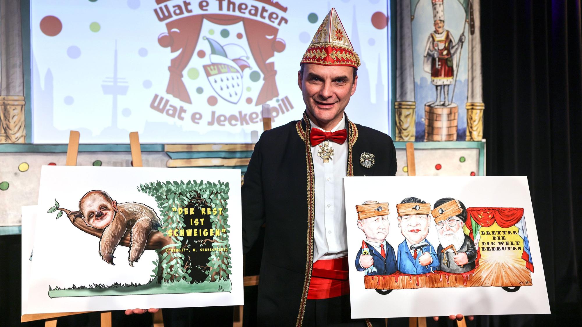 Holger Kirsch, Zugleiter des Kölner Rosenmontagszuges, zeigt zwei Zeichnung der politischen Persiflagewagen zu den Themen Bundeskanzler und Weltpolitik.