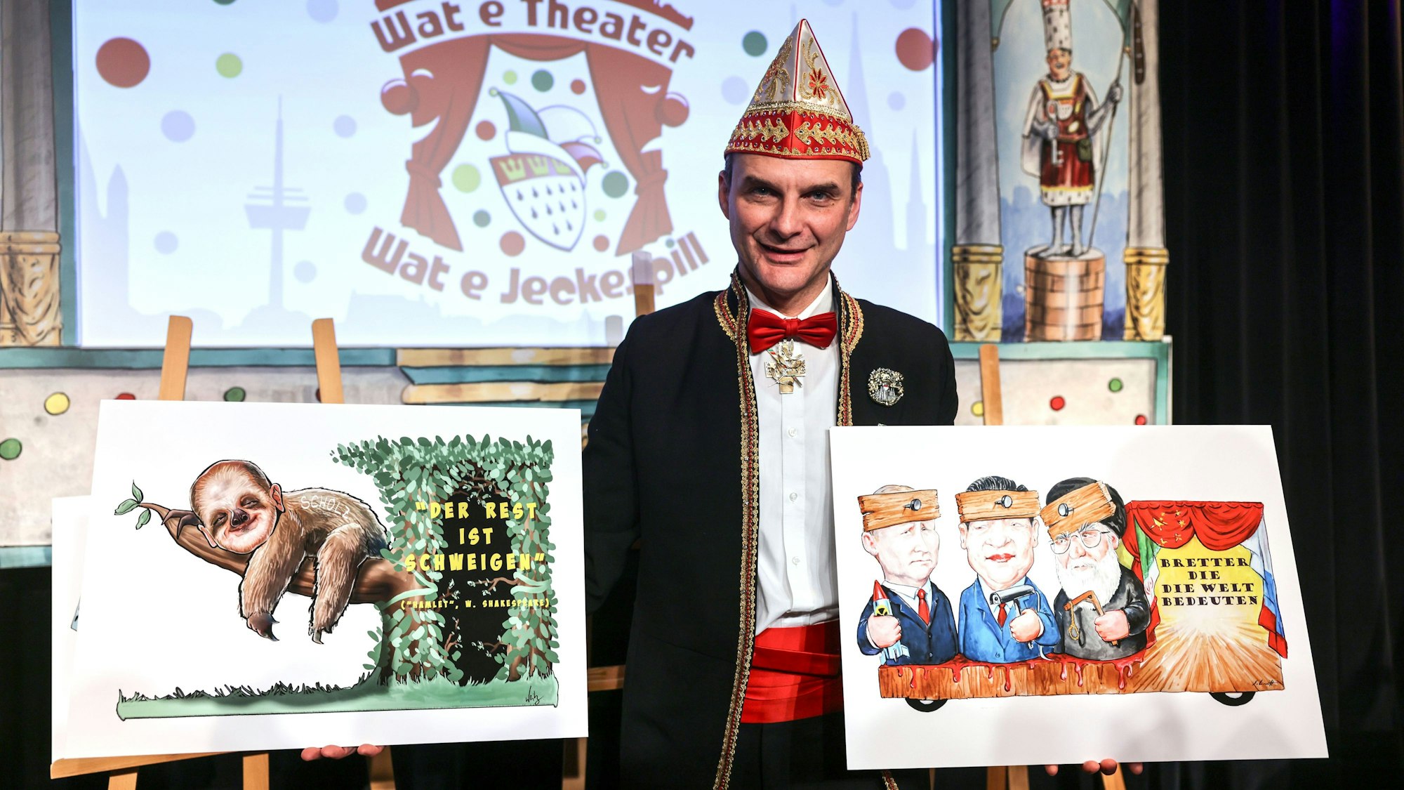 Holger Kirsch, Zugleiter des Kölner Rosenmontagszuges, zeigt zwei Zeichnung der politischen Persiflagewagen zu den Themen Bundeskanzler und Weltpolitik.