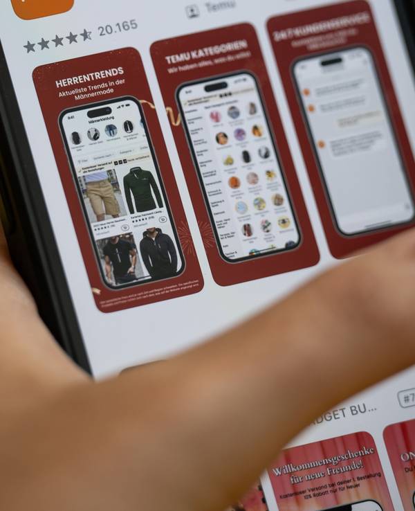 Eine Person hält ein Telefon mit der App Temu in den Händen (gestellte Szene).