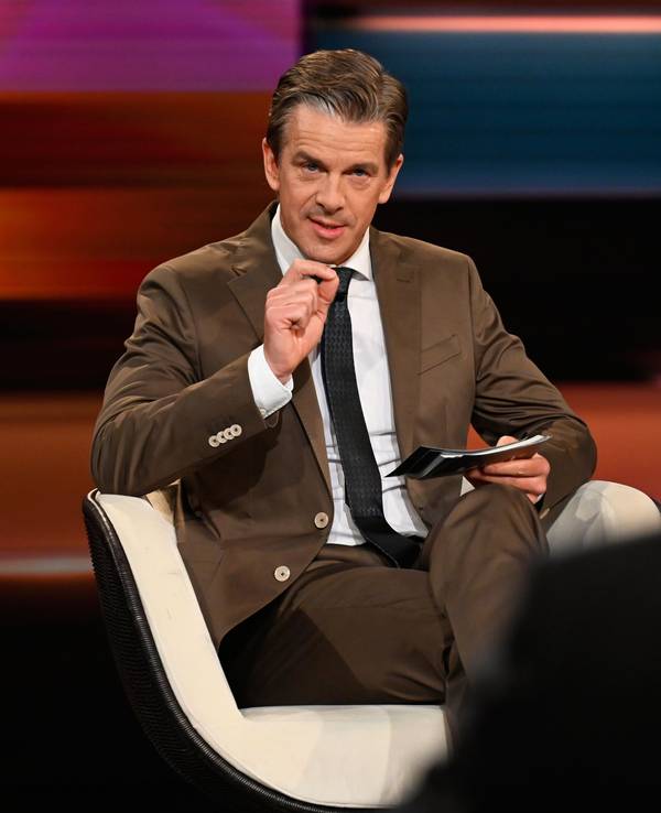 Markus Lanz sitzt bei der Moderation im Studio auf einem Stuhl.