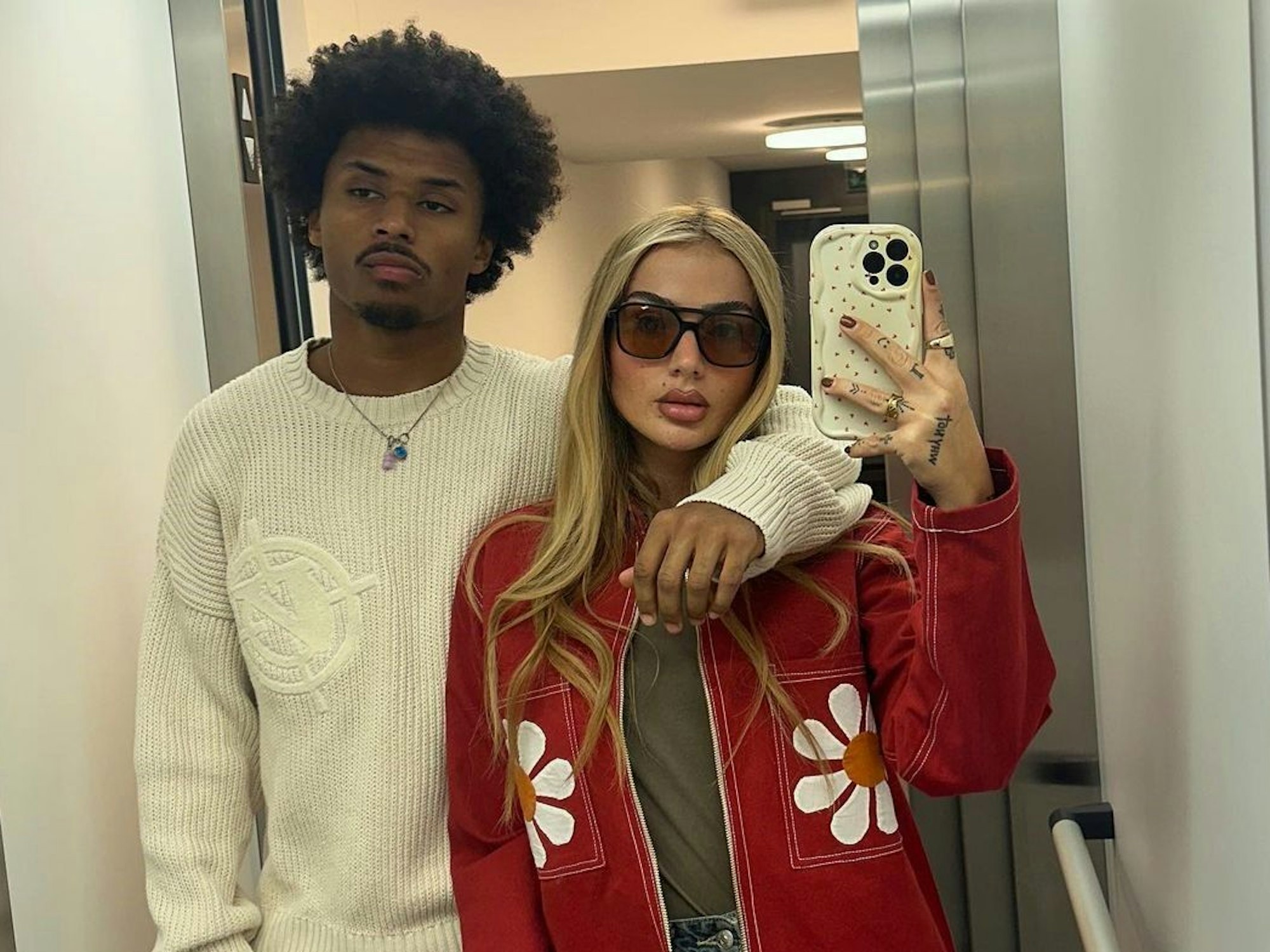 Loredana und Karim Adeyemi posieren zusammen für ein Spiegel-Selfie im Aufzug.