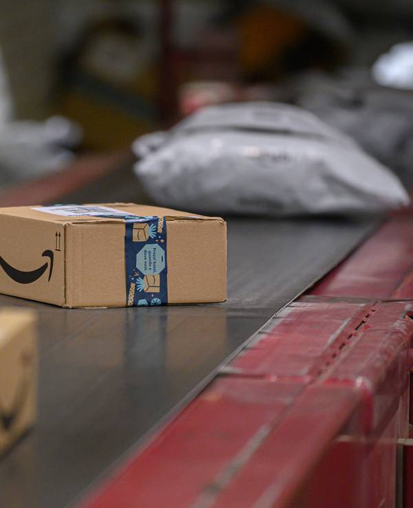 Amazon Pakete liegen im DHL-Paketzentrum auf einem Transportband.