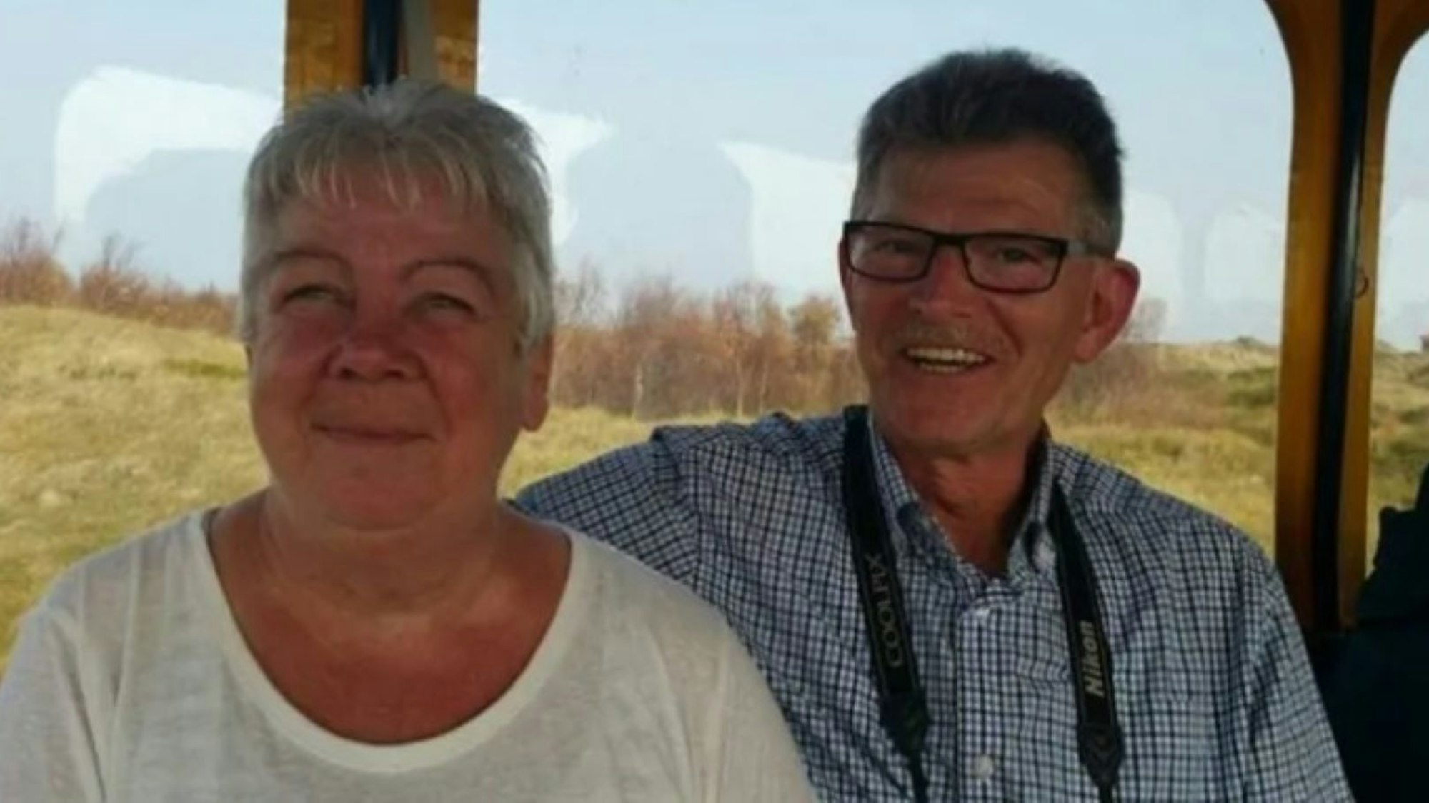 Richard Bitz legt seinen Arm um seine Frau Regina. Beide sitzen an einem Fenster mit Blick in die Natur.