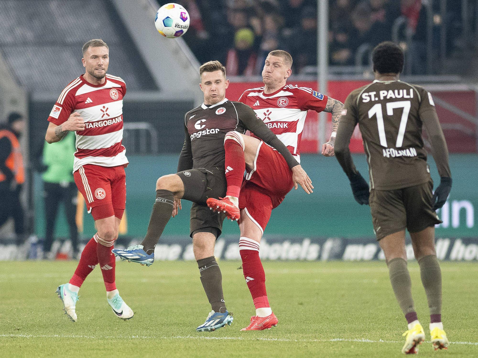 Die Düsseldorfer Innenverteidiger Andre Hoffmann und Jordy de Wijs versuchen, den Ball gegen St. Paulis Johannes Eggestein zu klären.