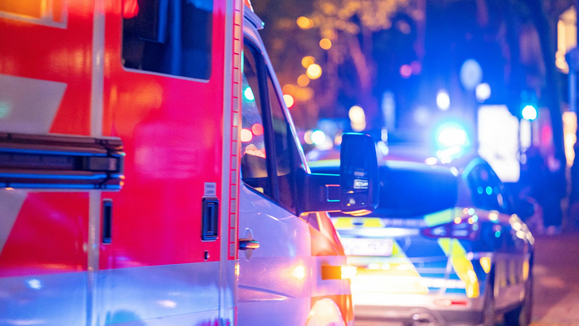 Ein Rettungs- und ein Streifenwagen stehen nachts am Straßenrand.