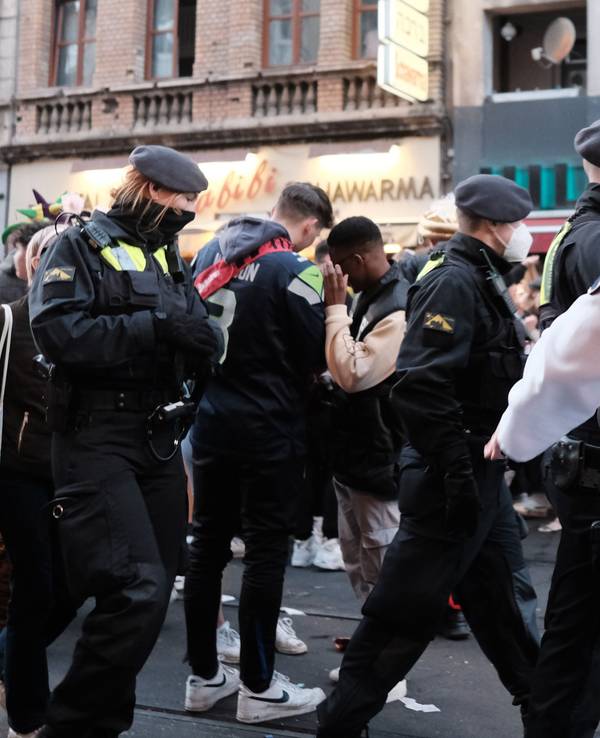 Junge Leute feiern Karneval im Kwartier Lateng, die Polizei läuft durch die Menge.