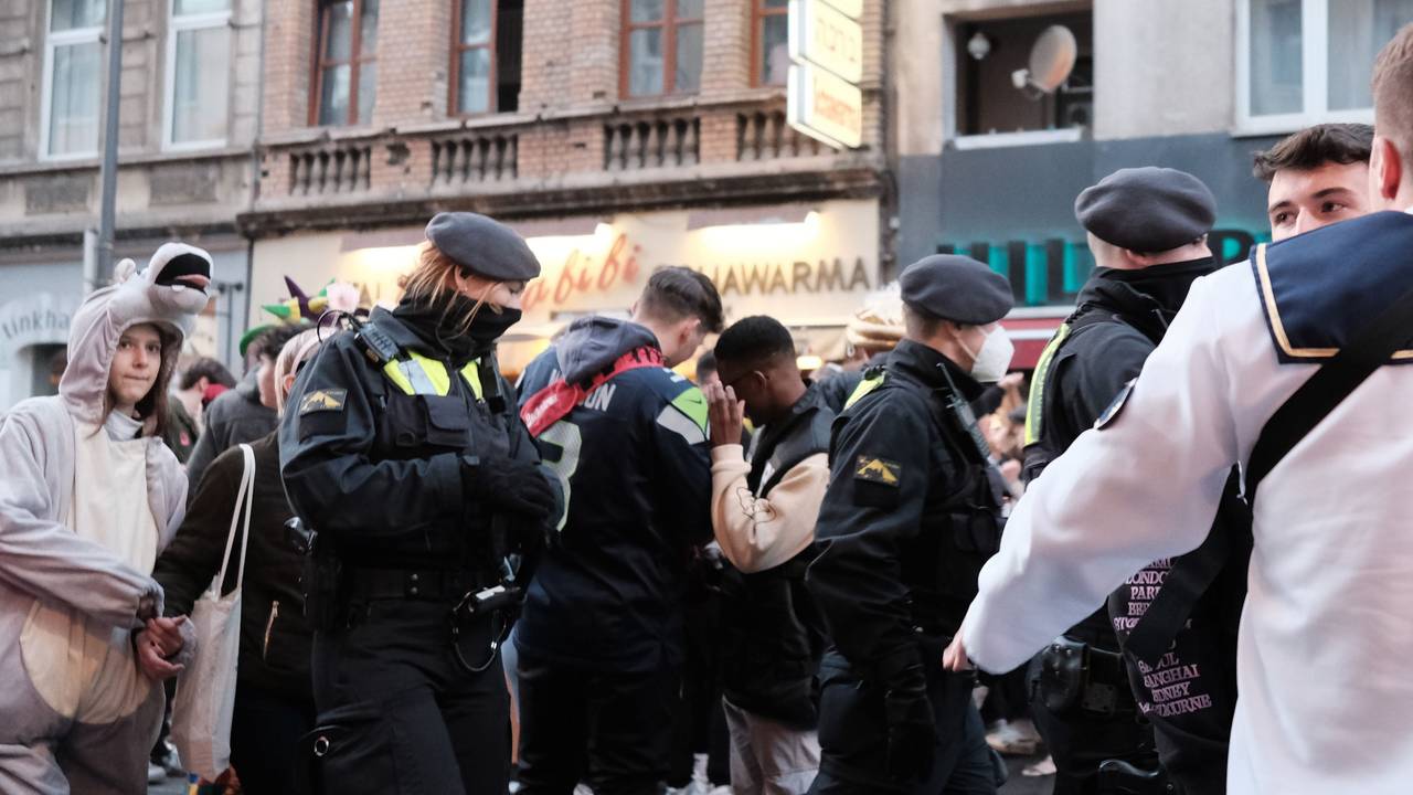 Junge Leute feiern Karneval im Kwartier Lateng, die Polizei läuft durch die Menge.