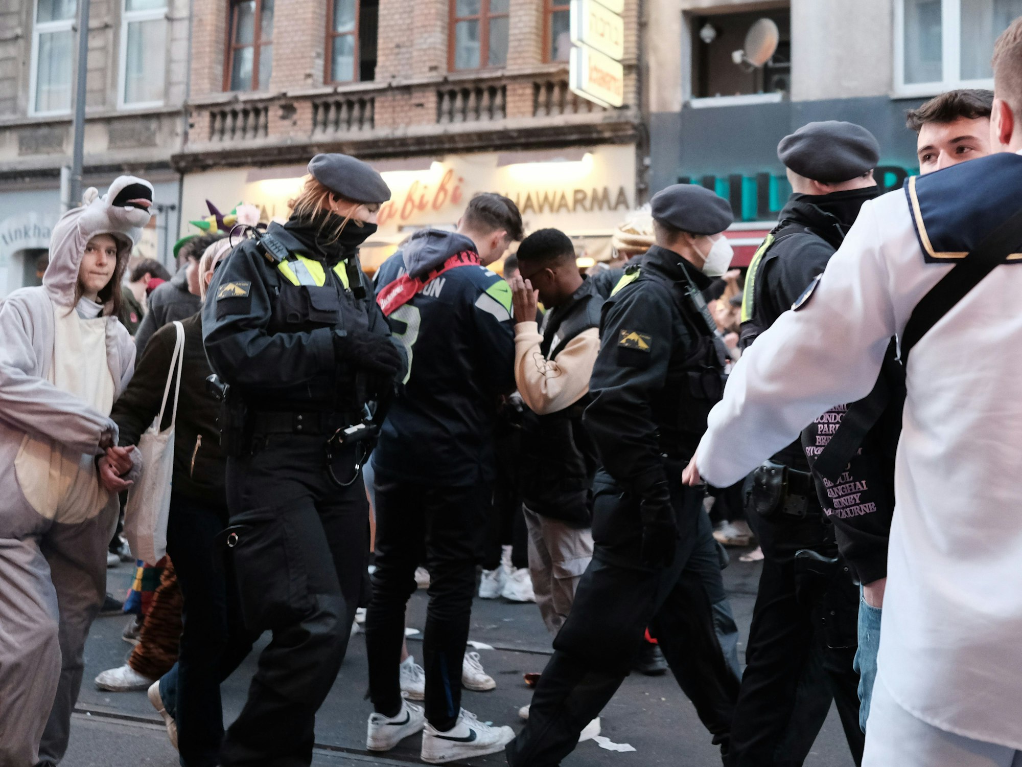 Junge Leute feiern Karneval im Kwartier Lateng, die Polizei läuft durch die Menge.