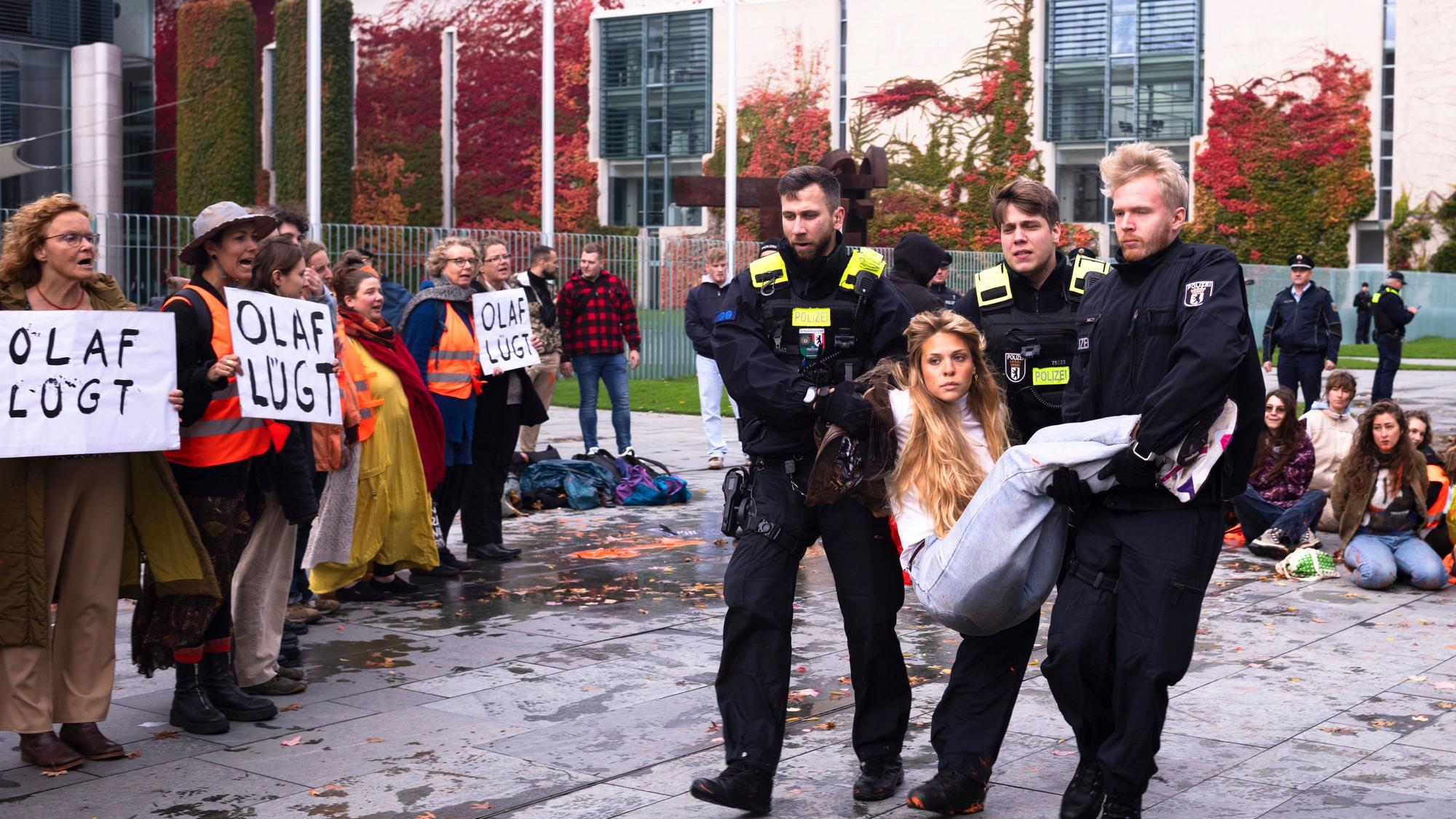 Polizisten tragen eine Aktivistin der Letzten Generation weg.