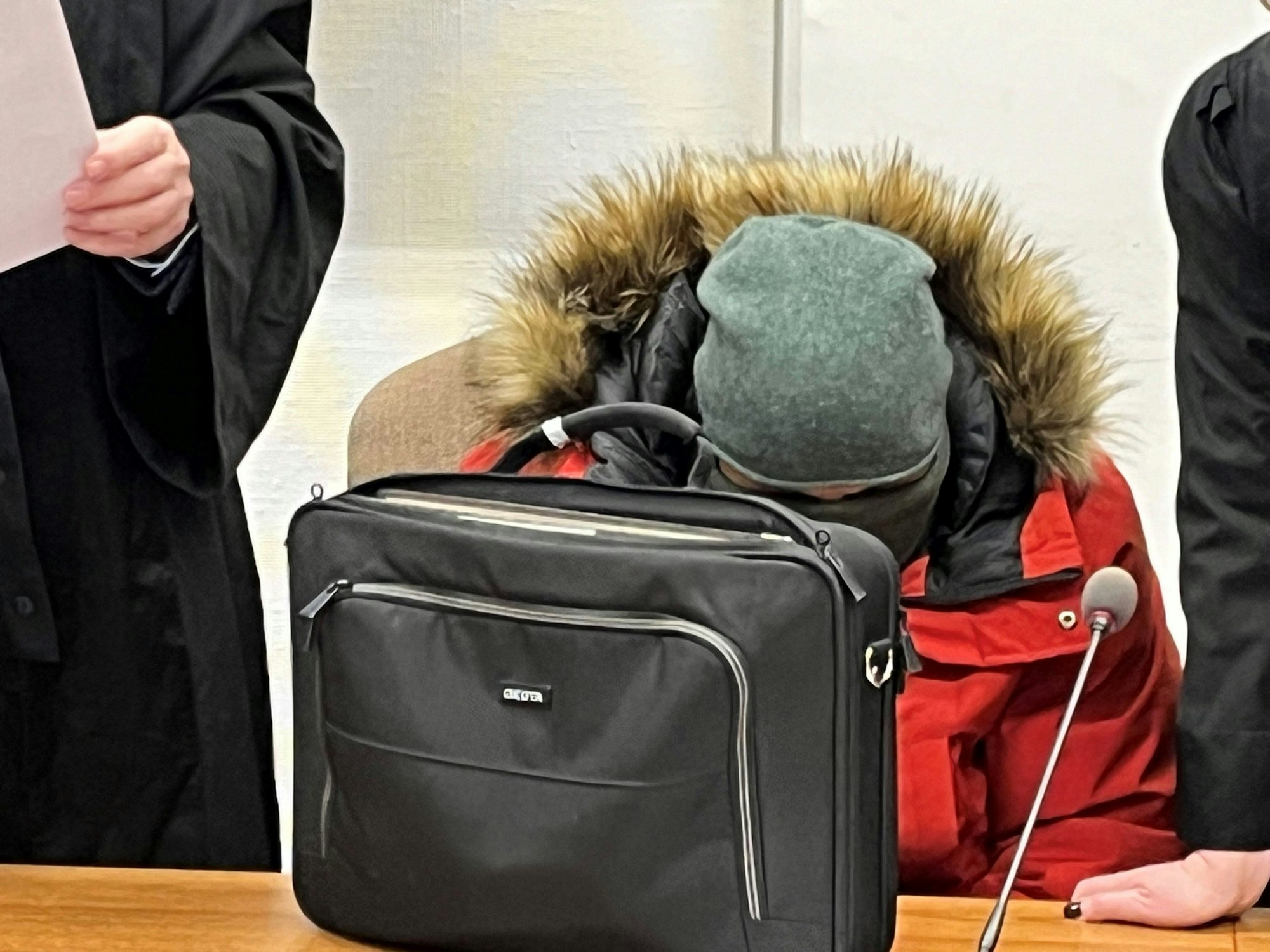Ein Mann sitzt in dicker Winterjacke auf der Anklagebank, Kopf und Gesicht sind mit Mütze und Schal vermummt.