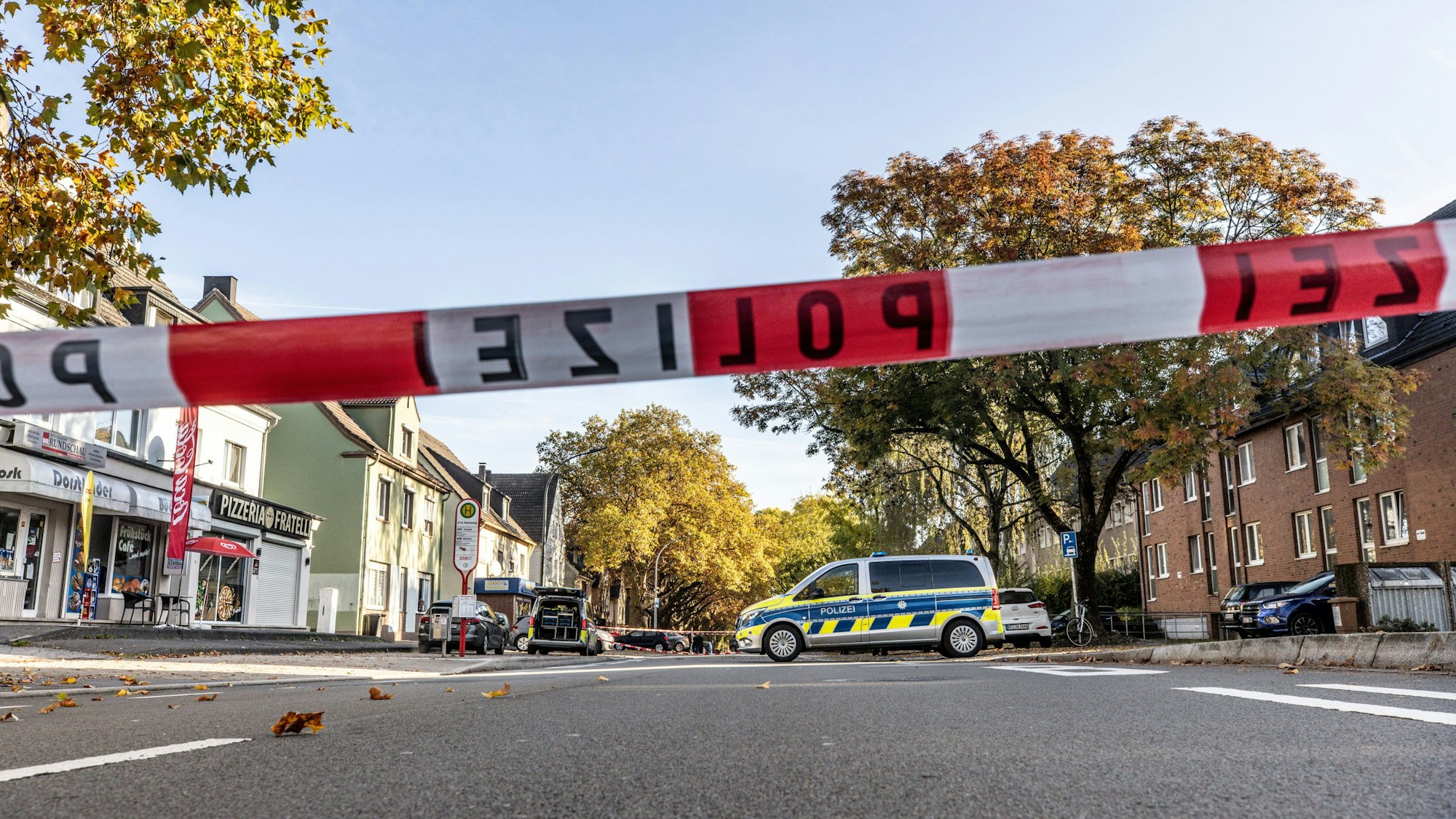 Polizei-Auto steht auf der Straße, die gleichzeitig auch von Absperrband dicht gemacht ist.