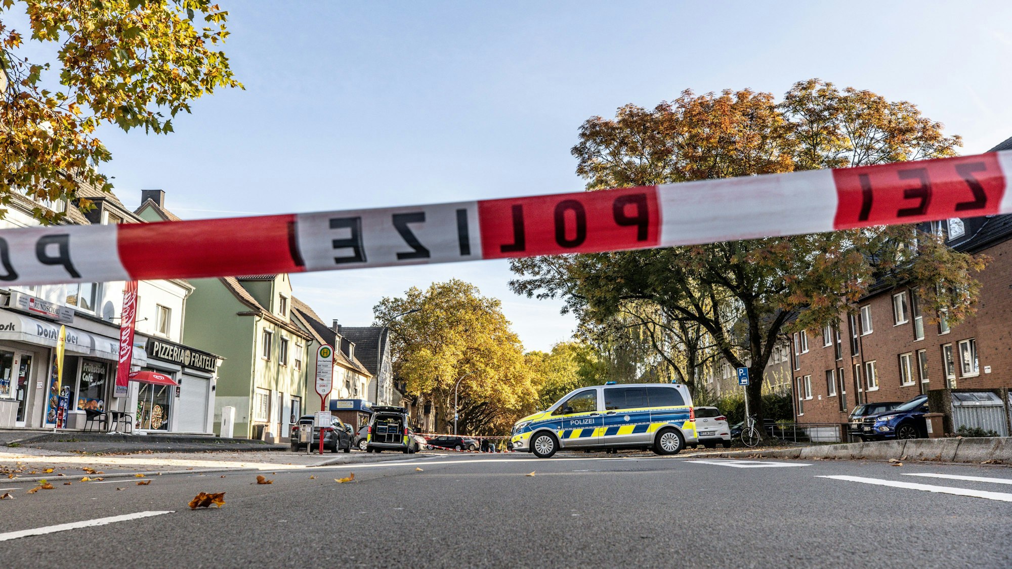 Absperrband der Polizei und Streifenwagen sichern einen Tatort.