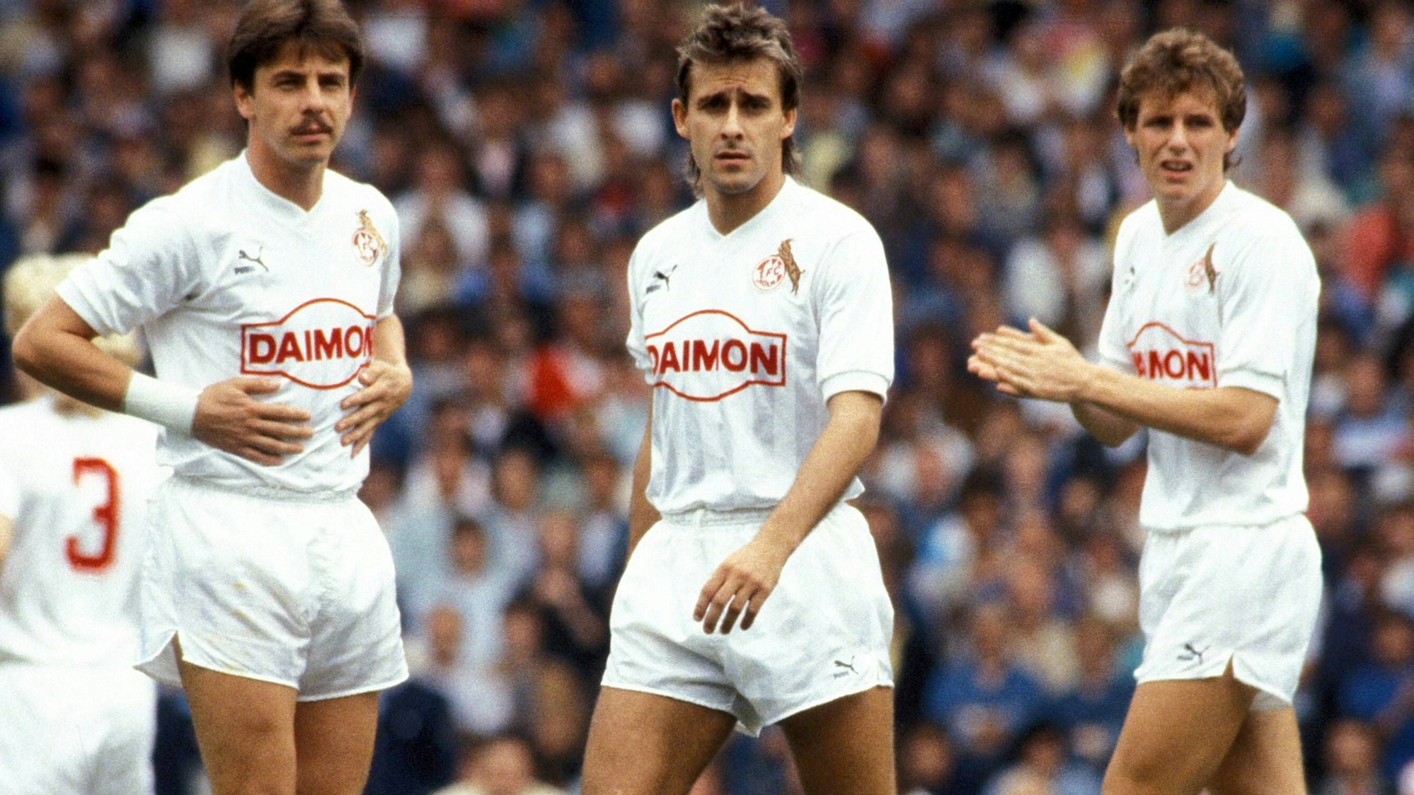 Ex-FC-Profi Dieter Prestin (l.) steht mit seinen damaligen Kölner Kollegen Pierre Littbarski und Flemming Povlsen auf dem Rasen.