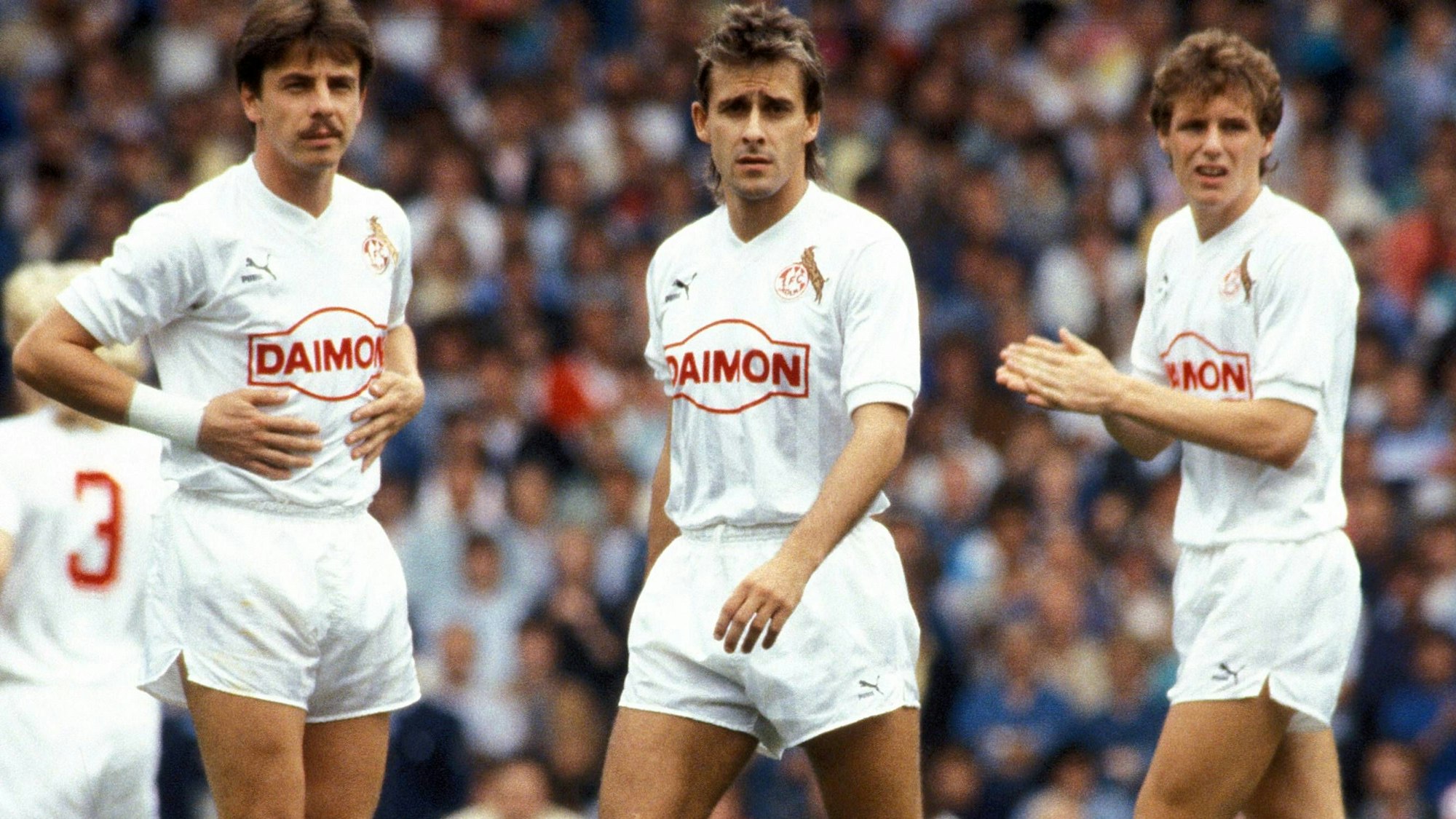 Ex-FC-Profi Dieter Prestin (l.) steht mit seinen damaligen Kölner Kollegen Pierre Littbarski und Flemming Povlsen auf dem Rasen.