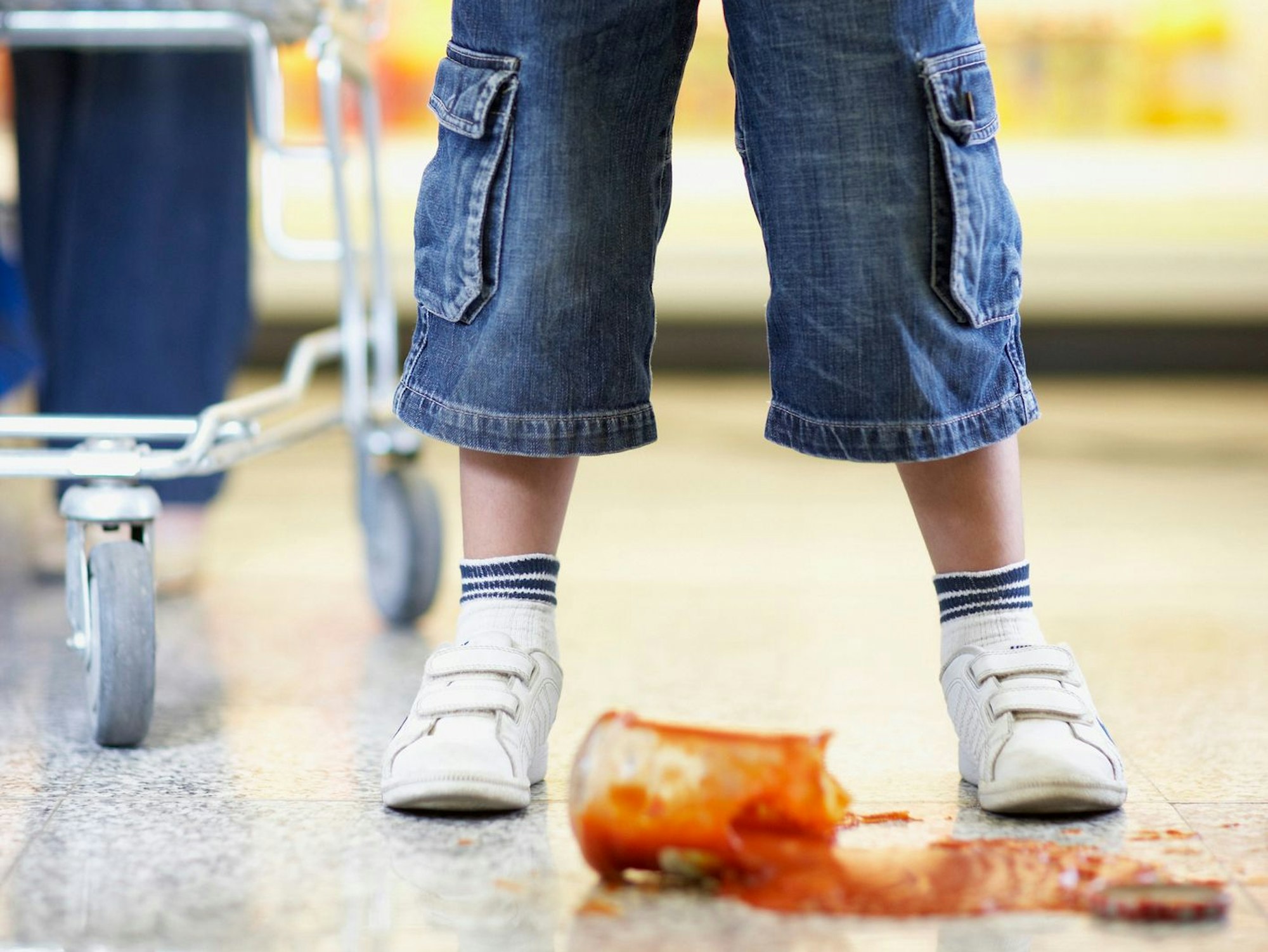 Ein Junge hat im Supermarkt ein Glas mit Tomatensoße zerbrochen