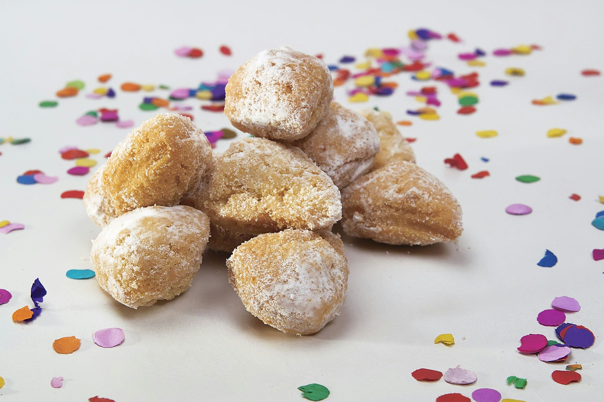 Mutzenmandeln liegen auf einer weißen Oberfläche, die mit Konfetti dekoriert ist