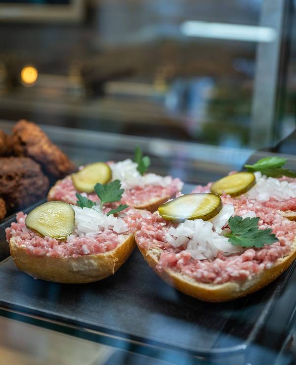 Mettbrötchen und Frikadellen liegen in der Auslage einer Metzgerei.