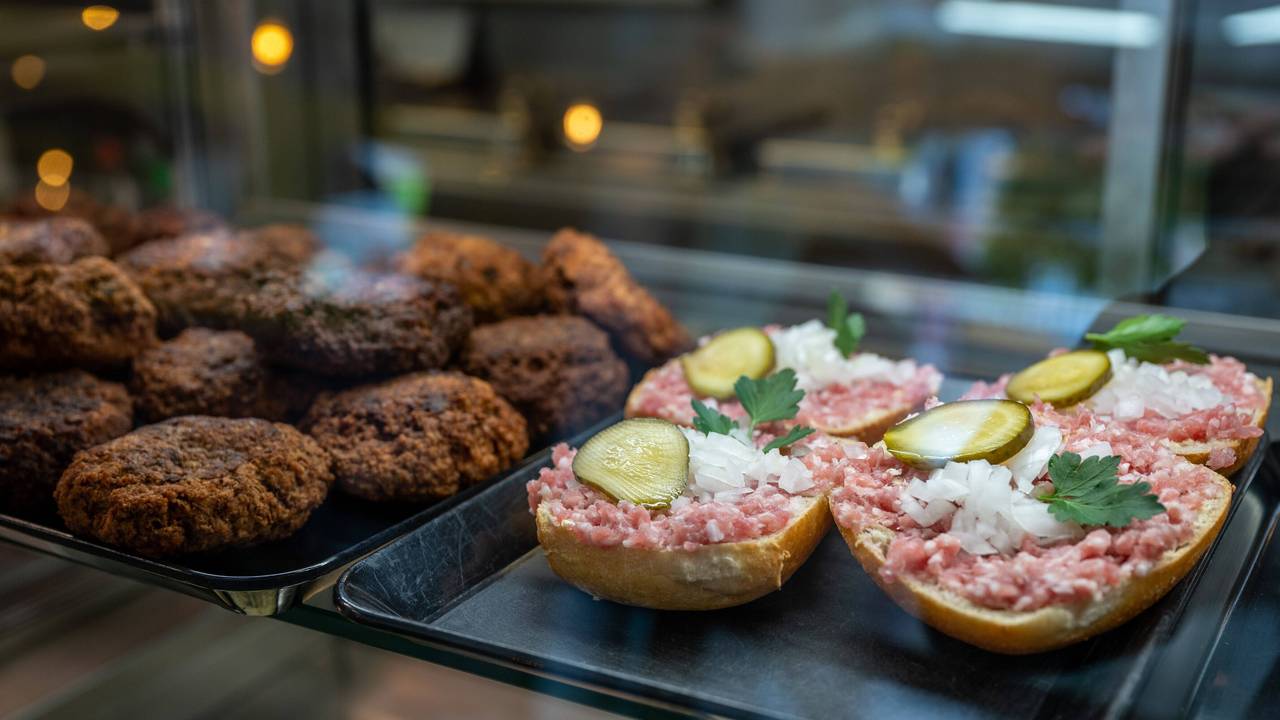Mettbrötchen und Frikadellen liegen in der Auslage einer Metzgerei.