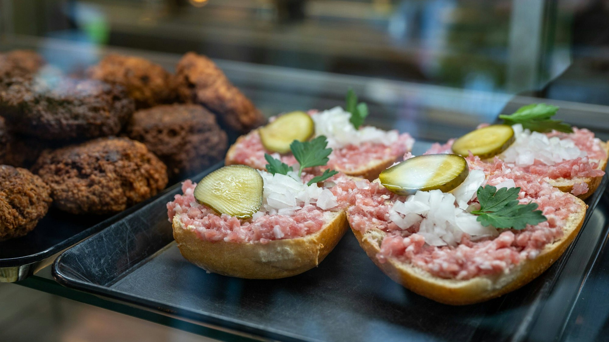 Mettbrötchen und Frikadellen liegen in der Auslage einer Metzgerei.