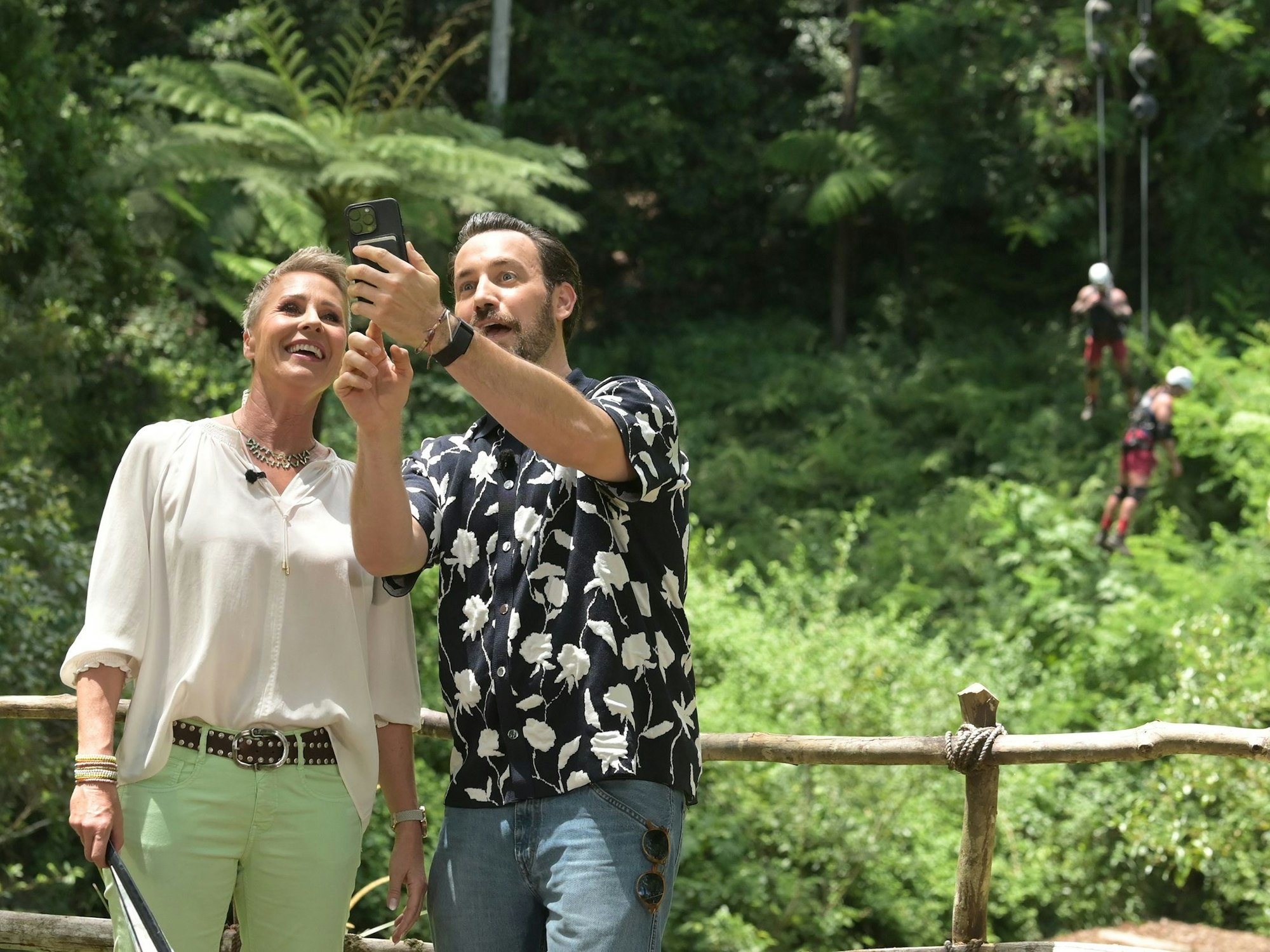 Die beiden Moderatoren Sonja Zietlow und Jan Köppen beobachten die Dschungelprüfung aus der Ferne.