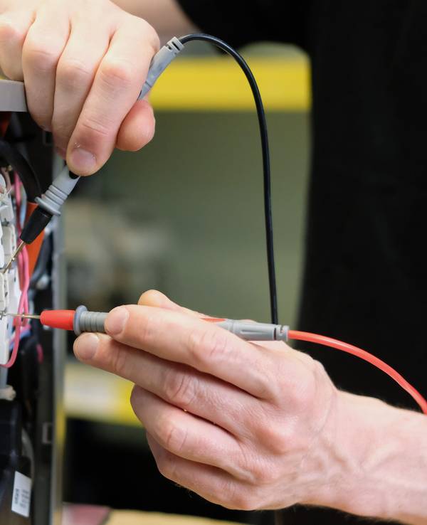 An einem Kaffee-Vollautomaten in einer Reparaturwerkstatt werden elektronische Messgrößen ermittelt.